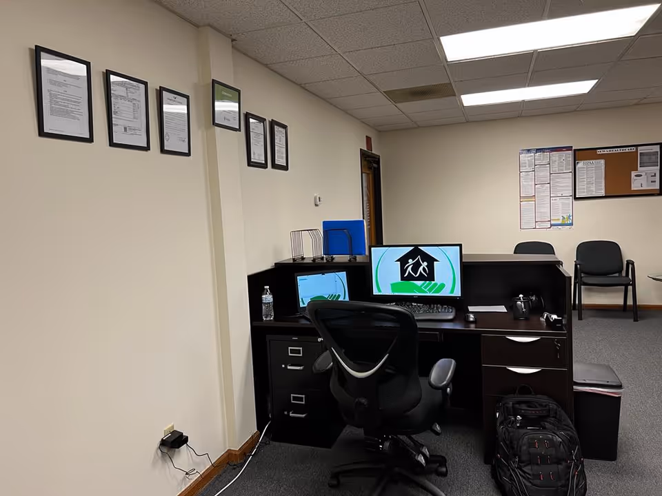 Office desk with dual monitors and chair in a clinical reception area.