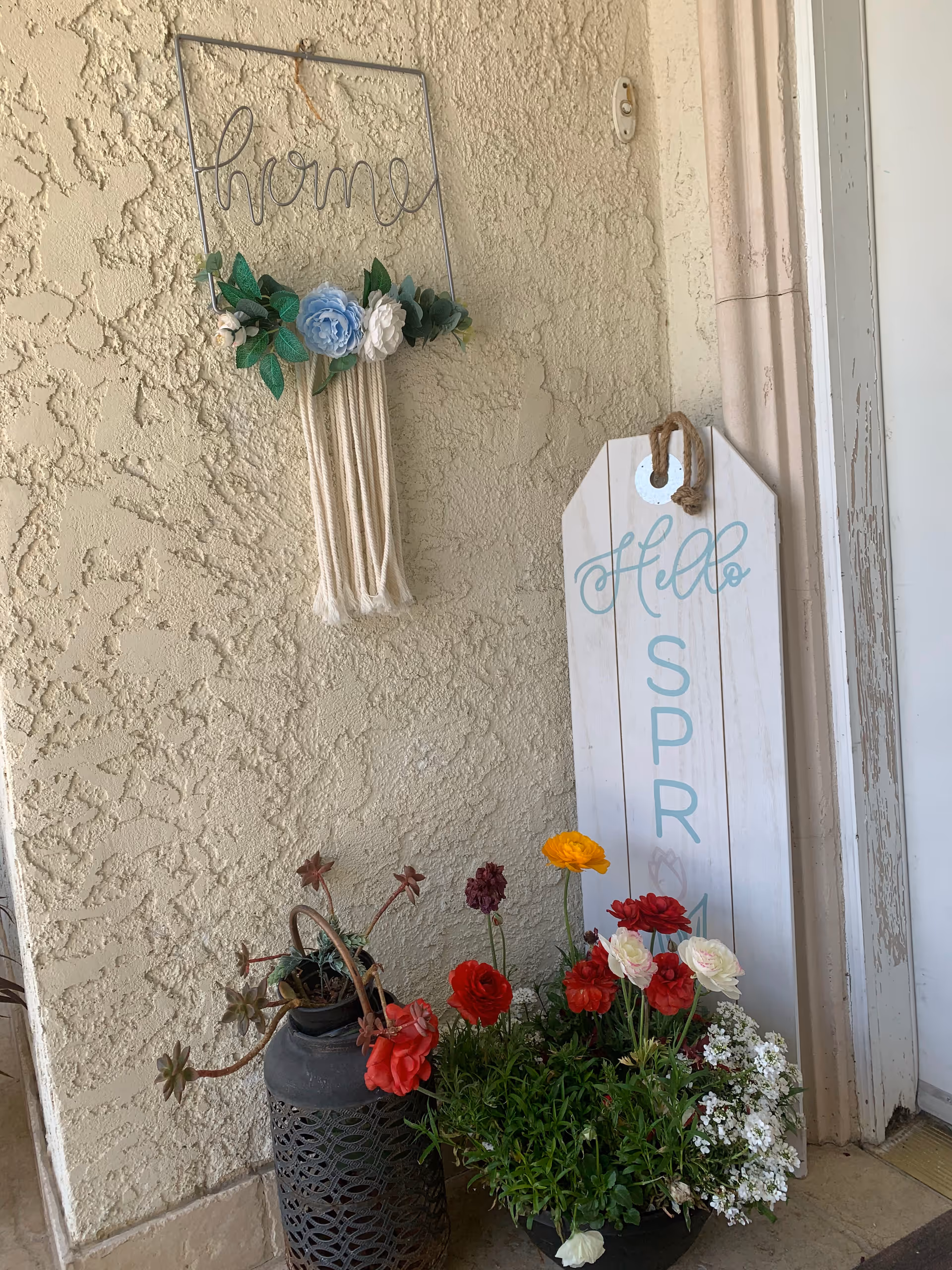 Exterior entry at Otilia's Board and Care with potted flowers and decorative signs.