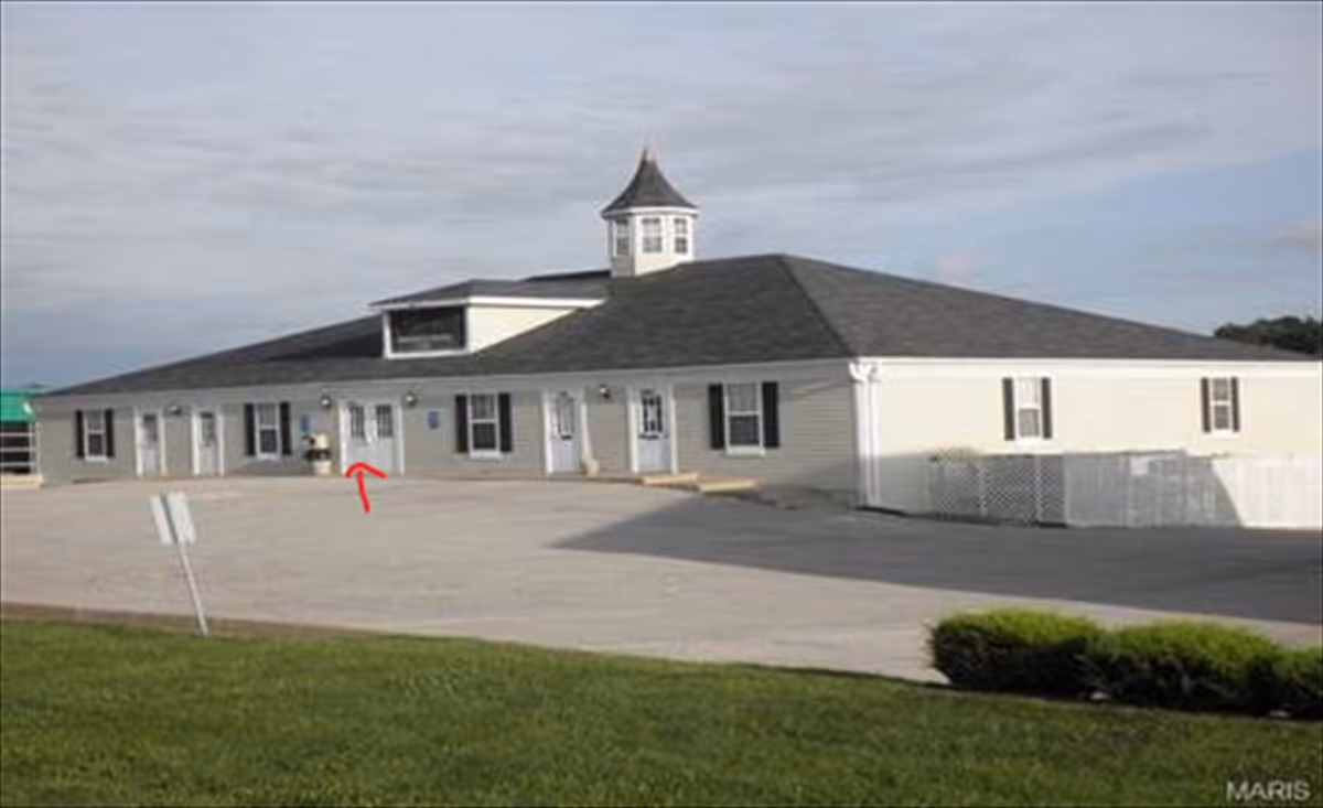 Exterior view of a single-story senior living facility with a wide parking area.
