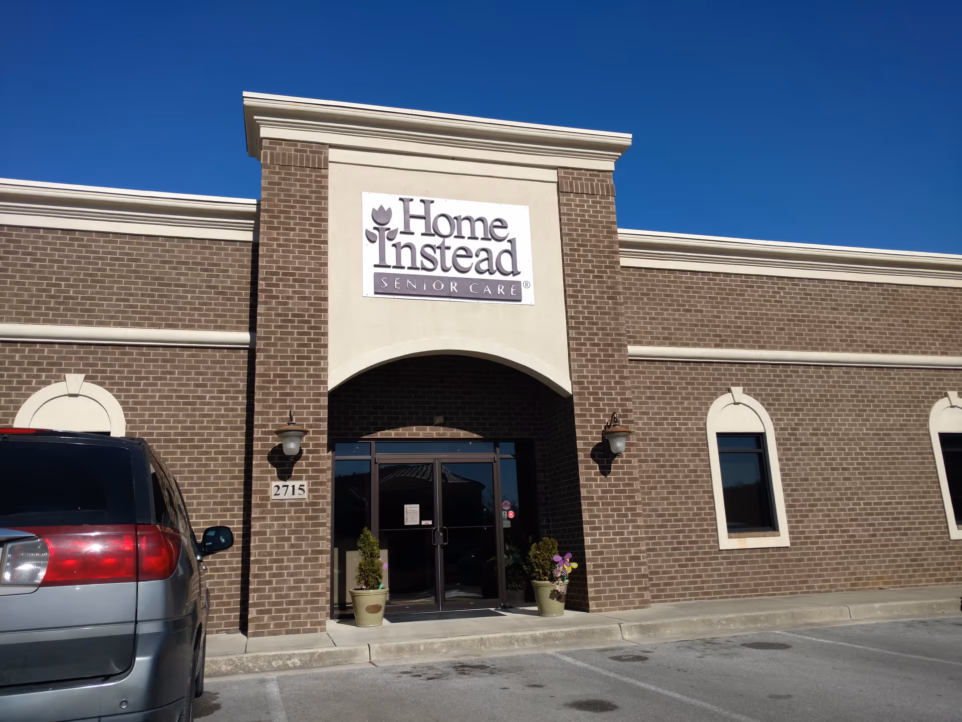 A brick building exterior featuring a Home Instead Senior Care sign and entrance doors.