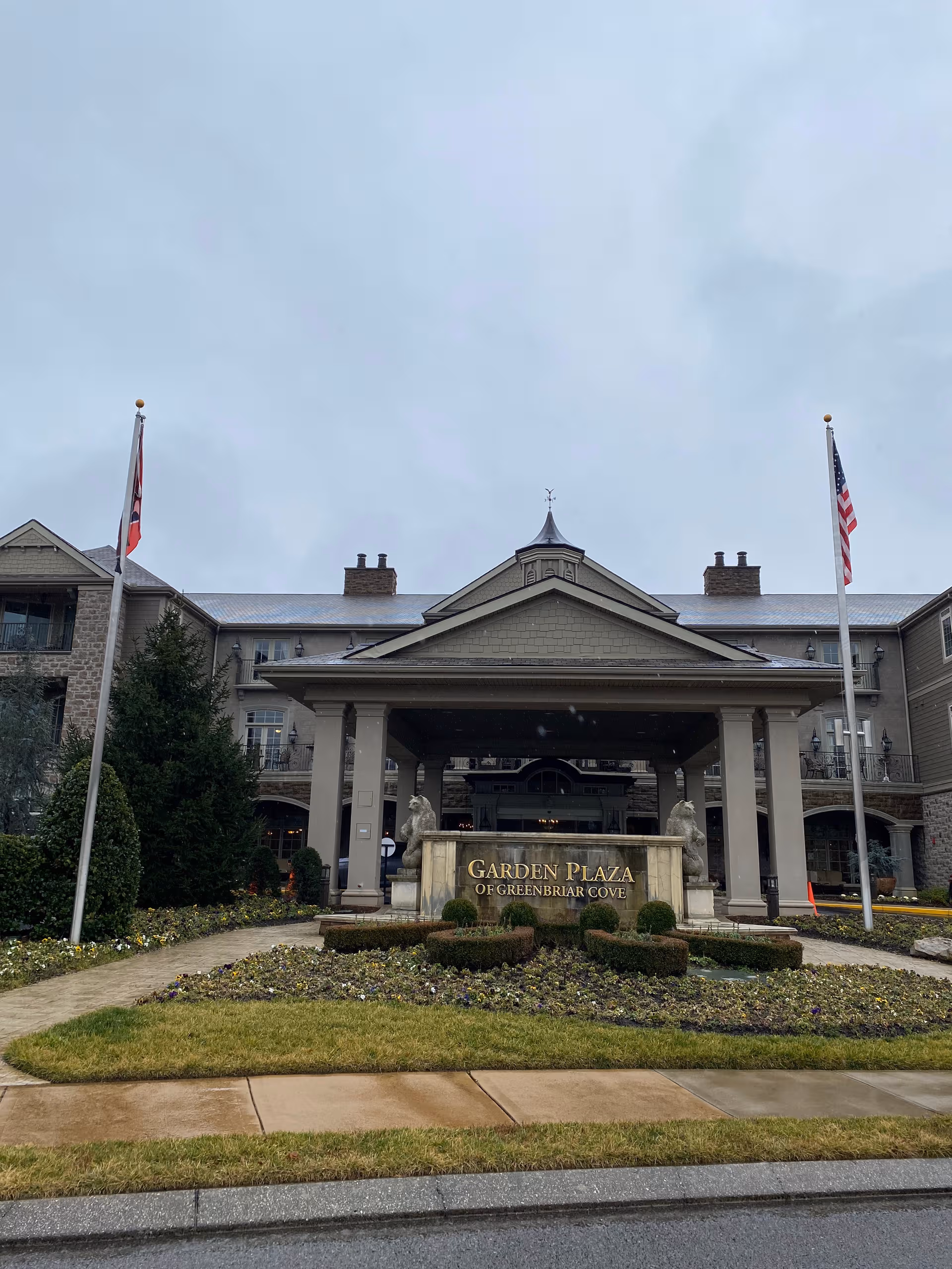 Front view of Garden Plaza of Greenbriar Cove entrance with flags and landscaping.