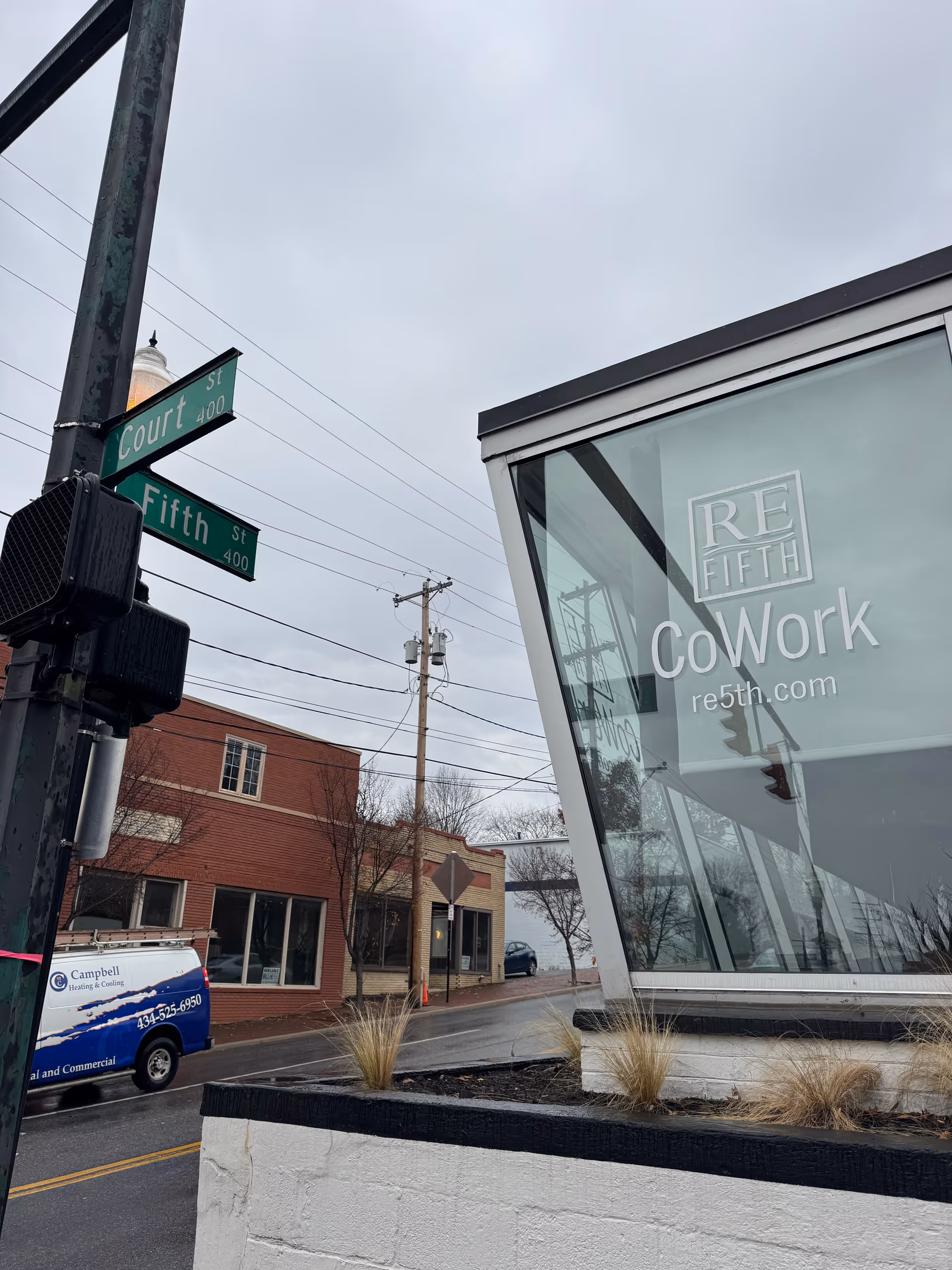 Street corner view with modern glass building facade and street signs at Fifth and Court.