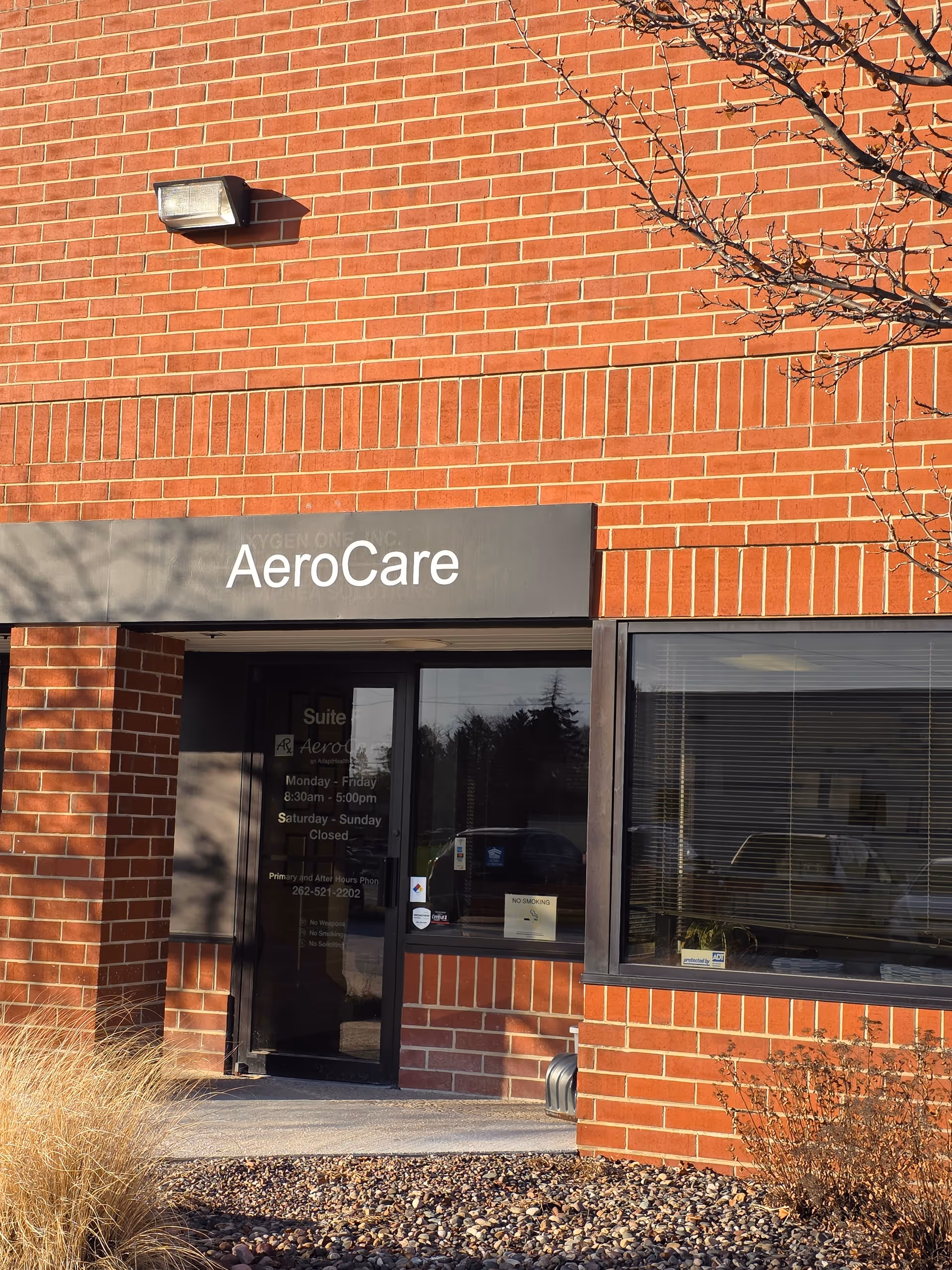 Brick building facade with AeroCare sign and glass entrance door.