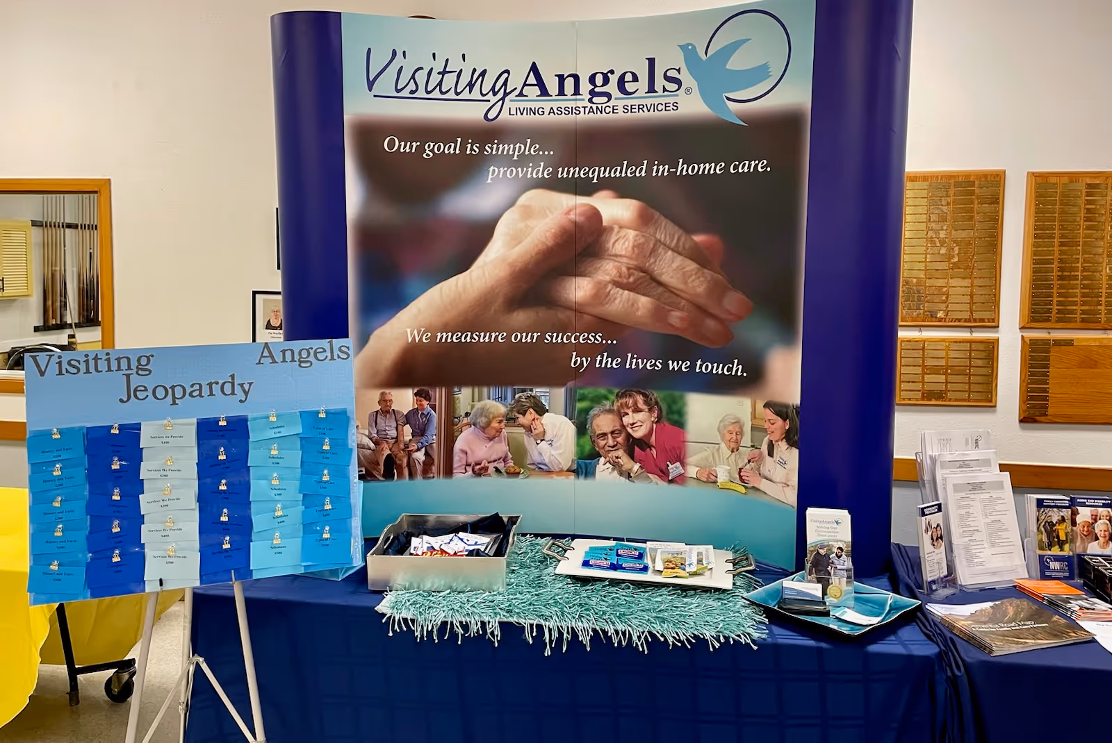 Promotional booth for Visiting Angels senior home care with a banner and game boards.