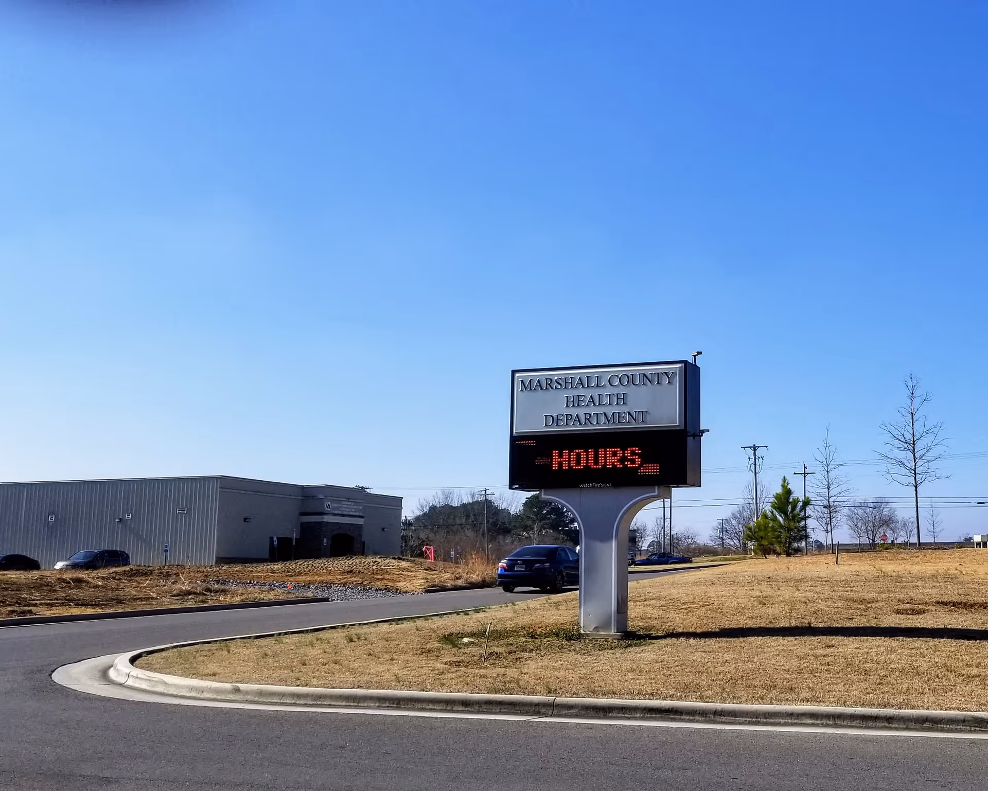 Exterior view of Marshall County Health Department building with a curved sign pedestal