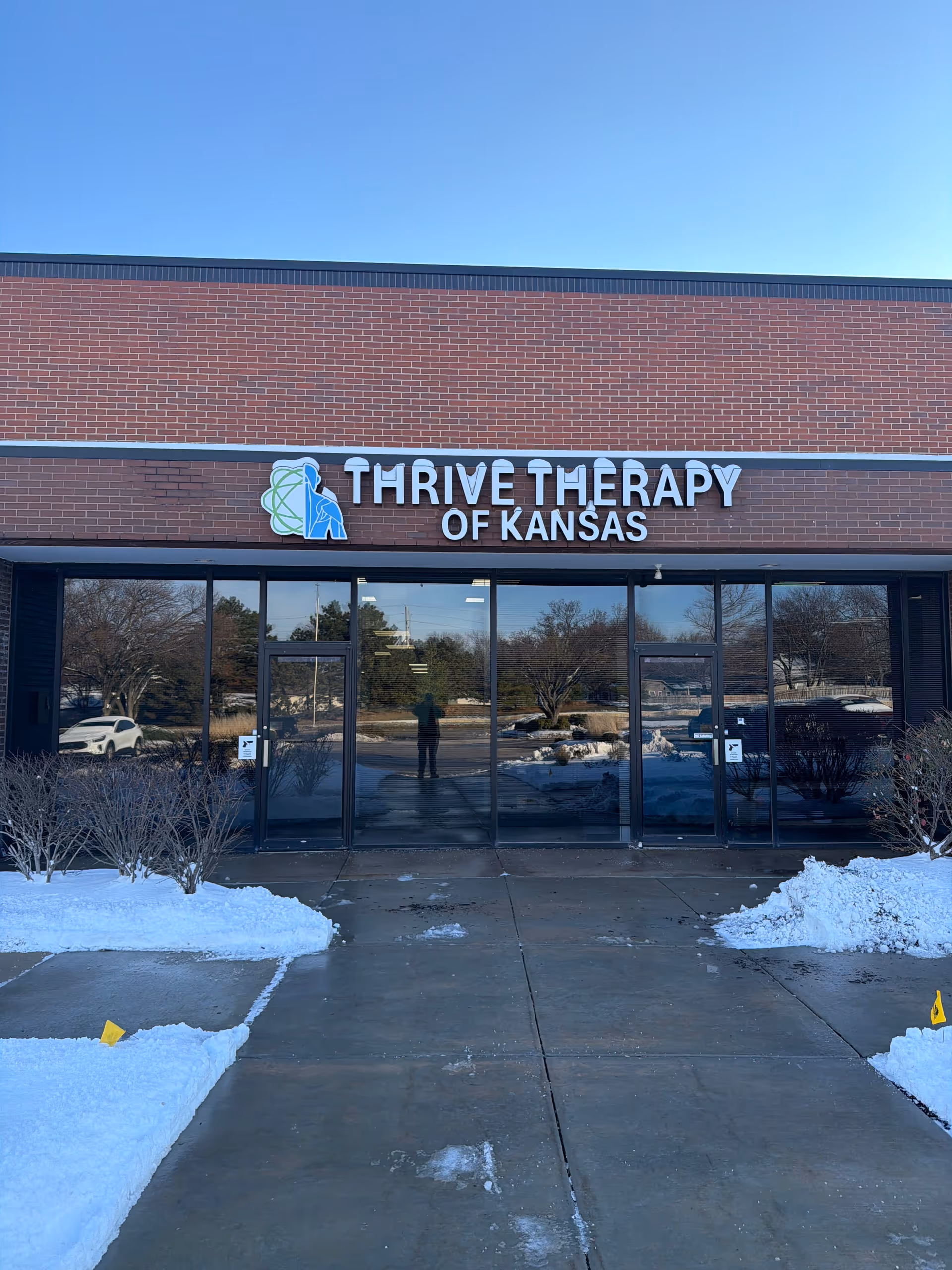 Exterior view of Thrive Therapy of Kansas entrance with snow outside.