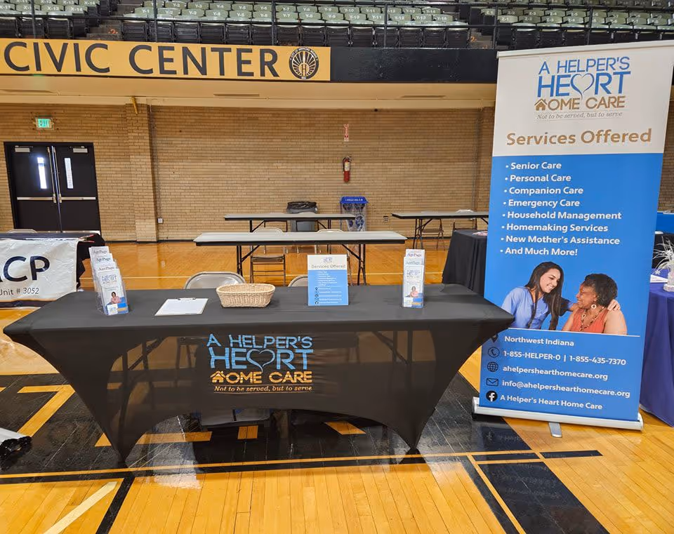Promotional booth for A Helper's Heart Home Care set up in a gym interior with banners.