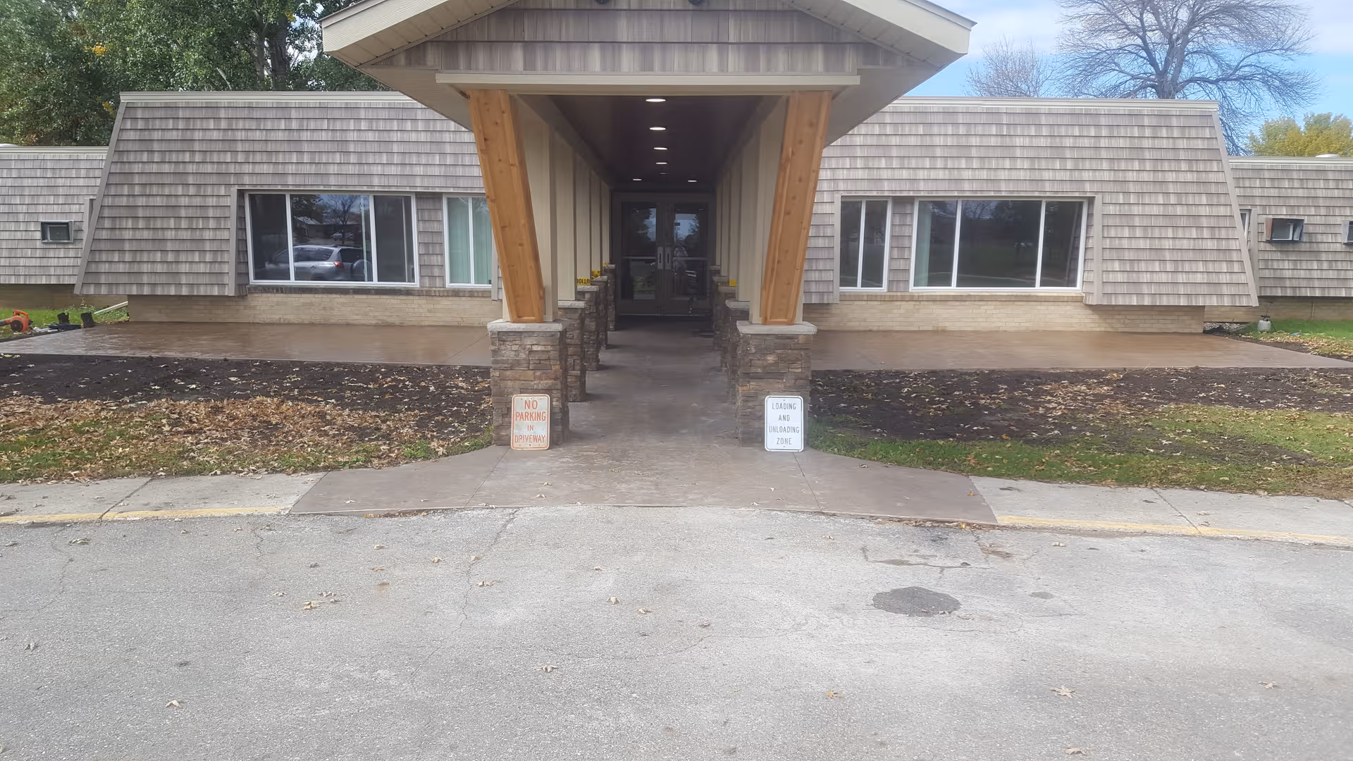 Front entrance of a retirement center with a covered walkway and stone pillars.