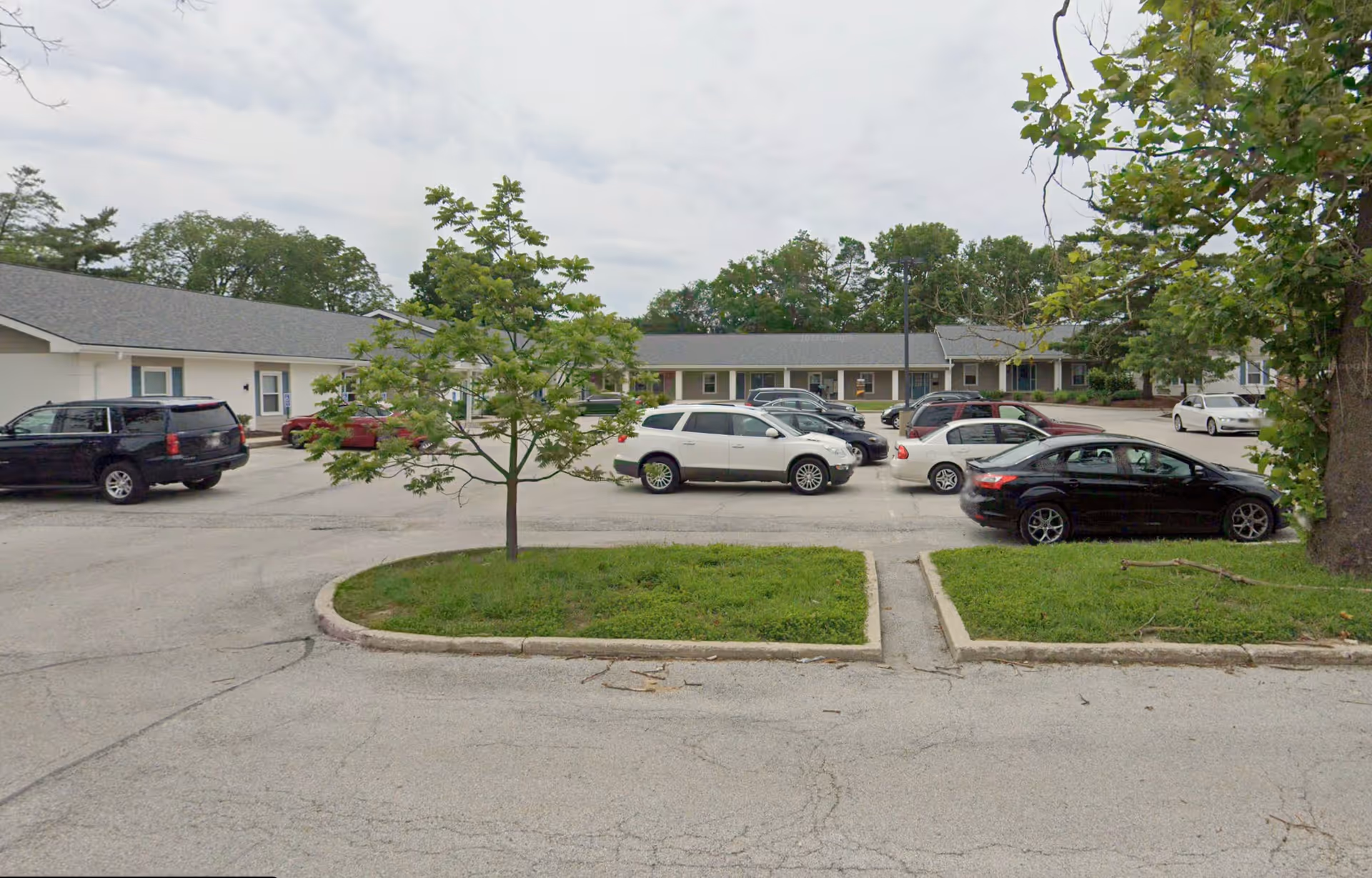 Parking lot in front of a single-story care facility with multiple parked cars.