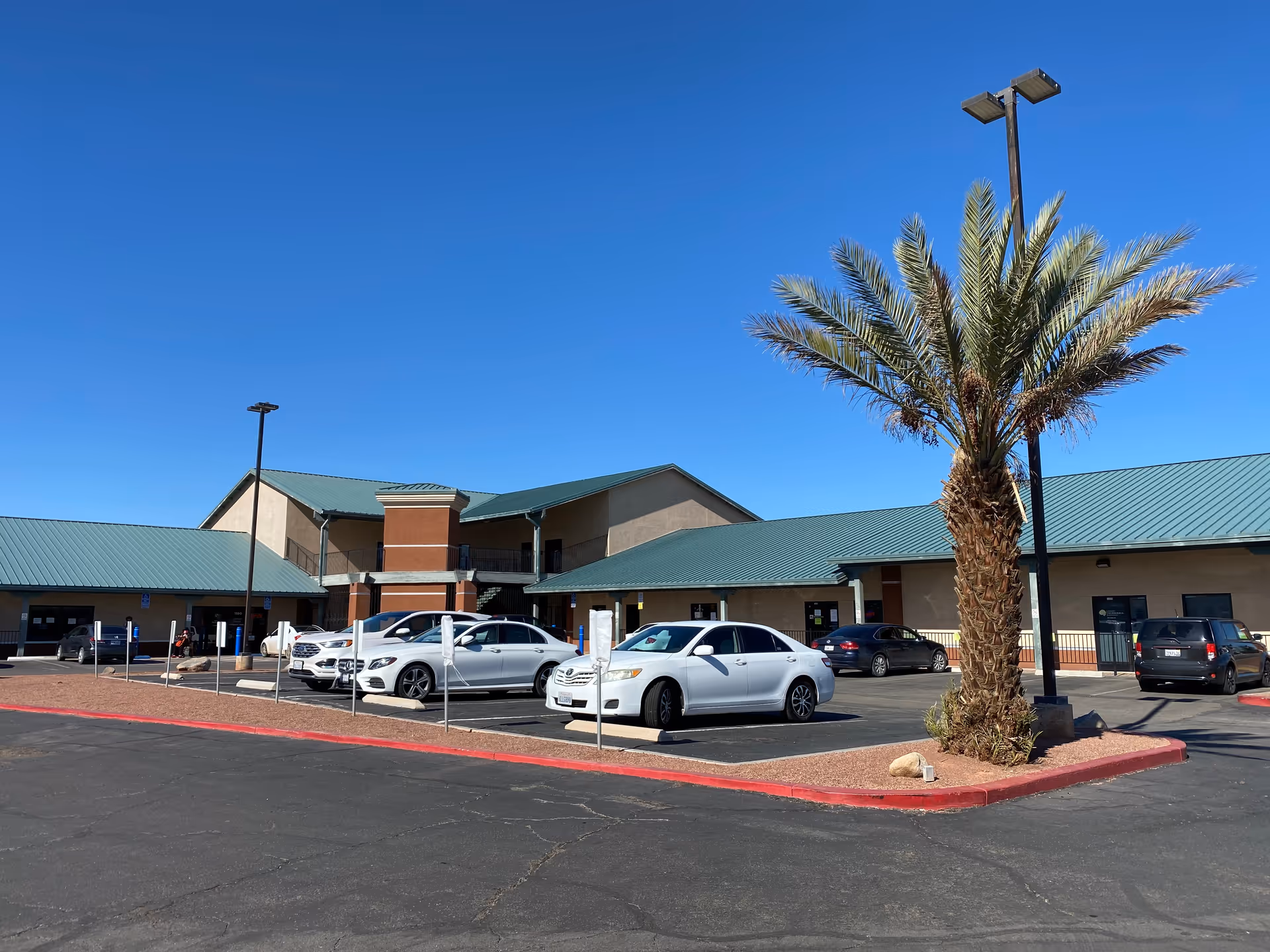 Exterior view of Uni Care Home Care facility with parked cars and a palm tree.