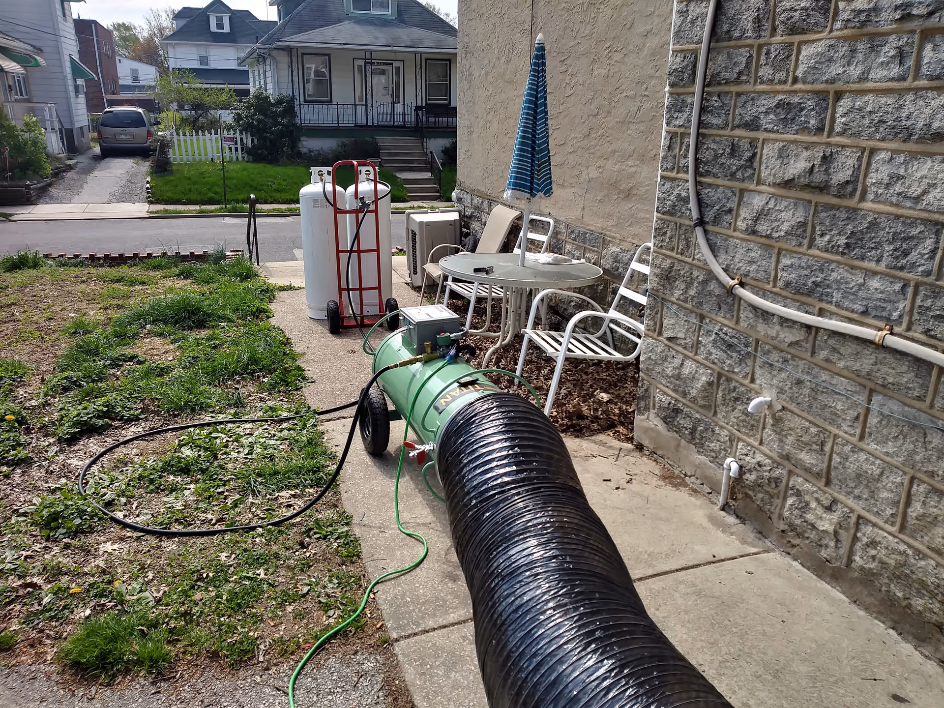 Outdoor backyard area with a metal table, chairs, umbrella, and pest-control equipment.