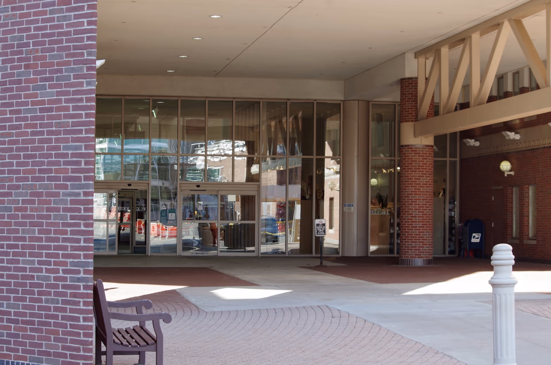 Exterior view of a hospital entrance with glass doors, brick columns, and an overhang.