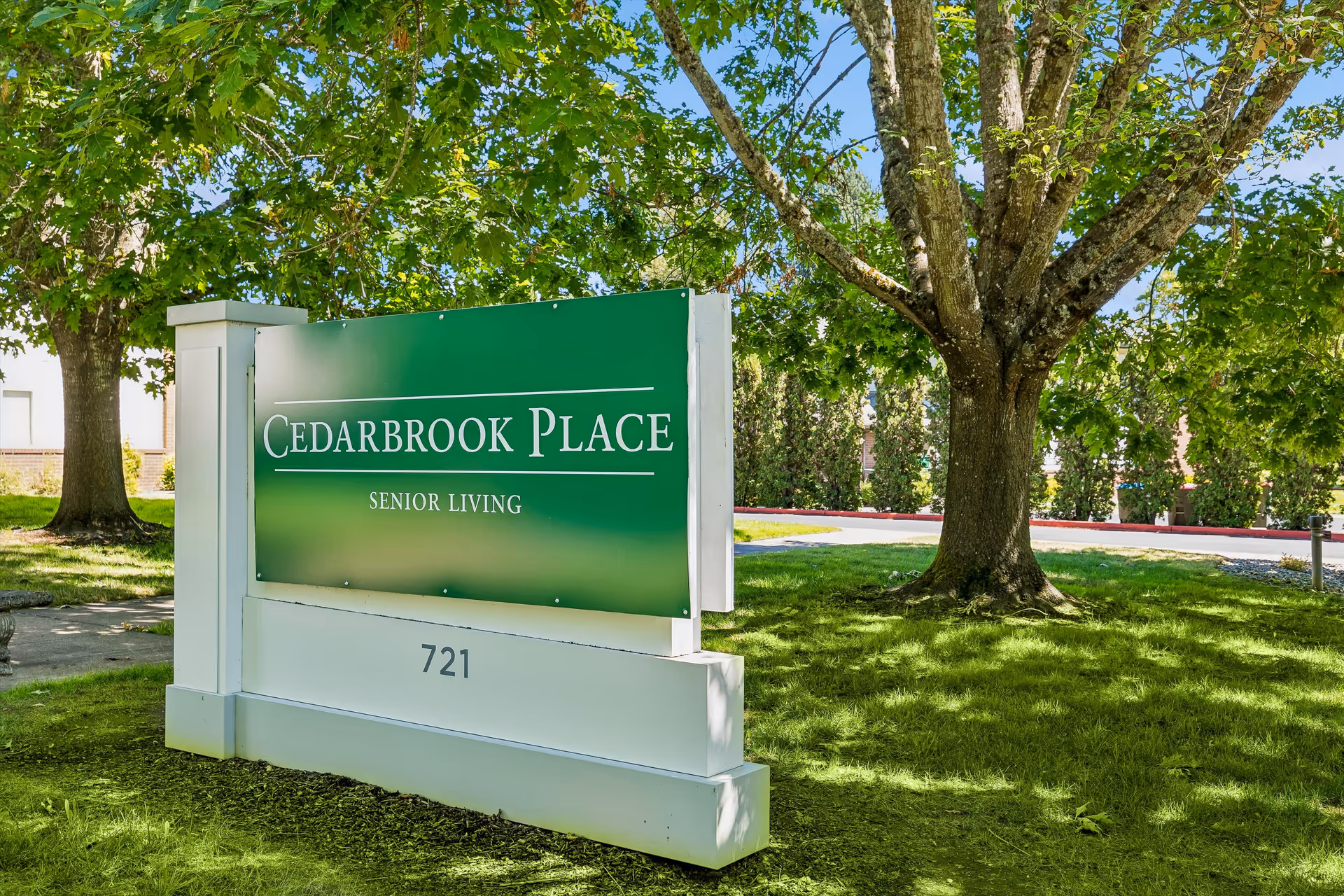 Green Cedarbrook Place Senior Living sign on a lawn with trees.