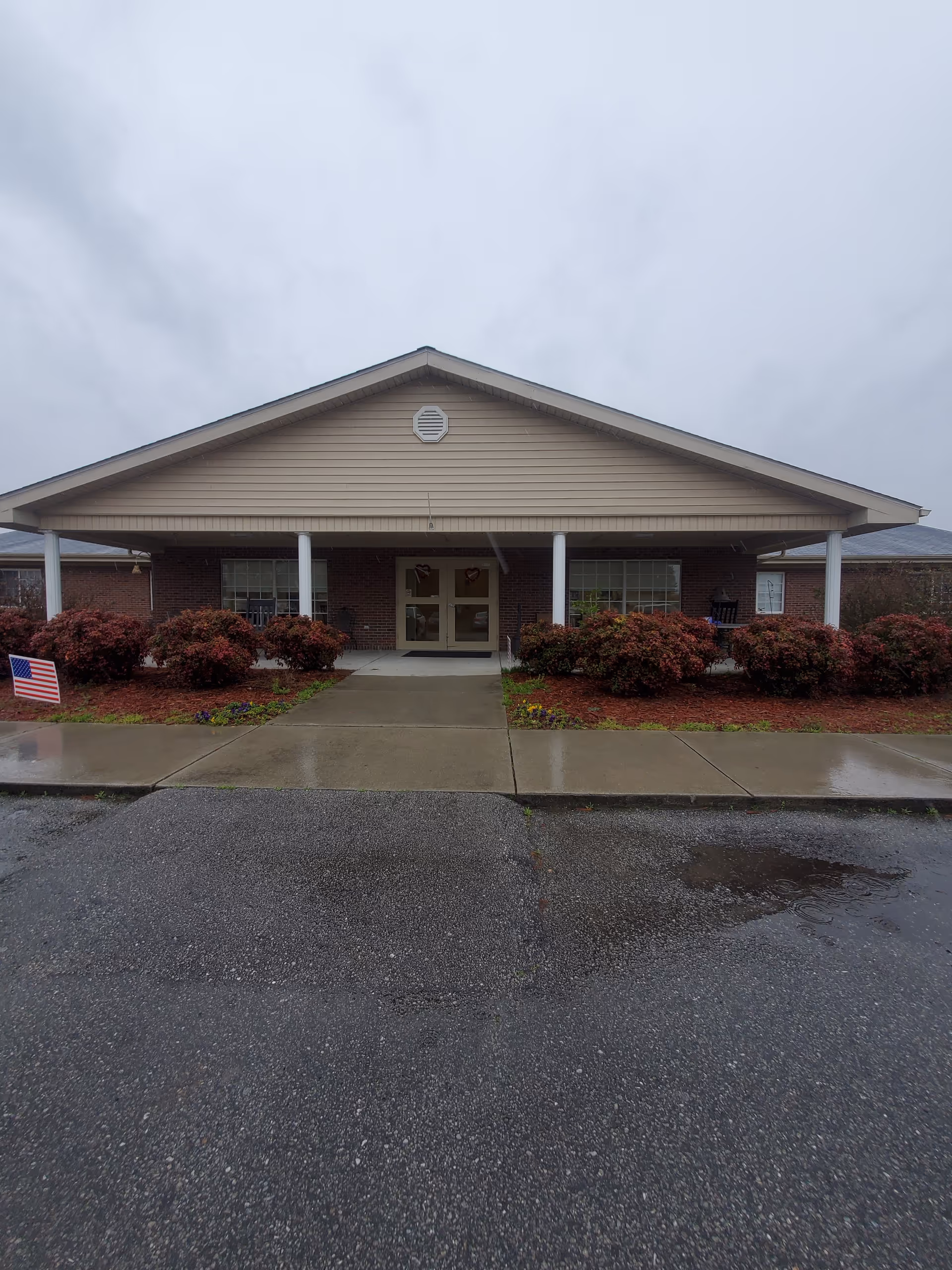 Front view of The Gardens of Rose Hill facility with entrance and landscaping.