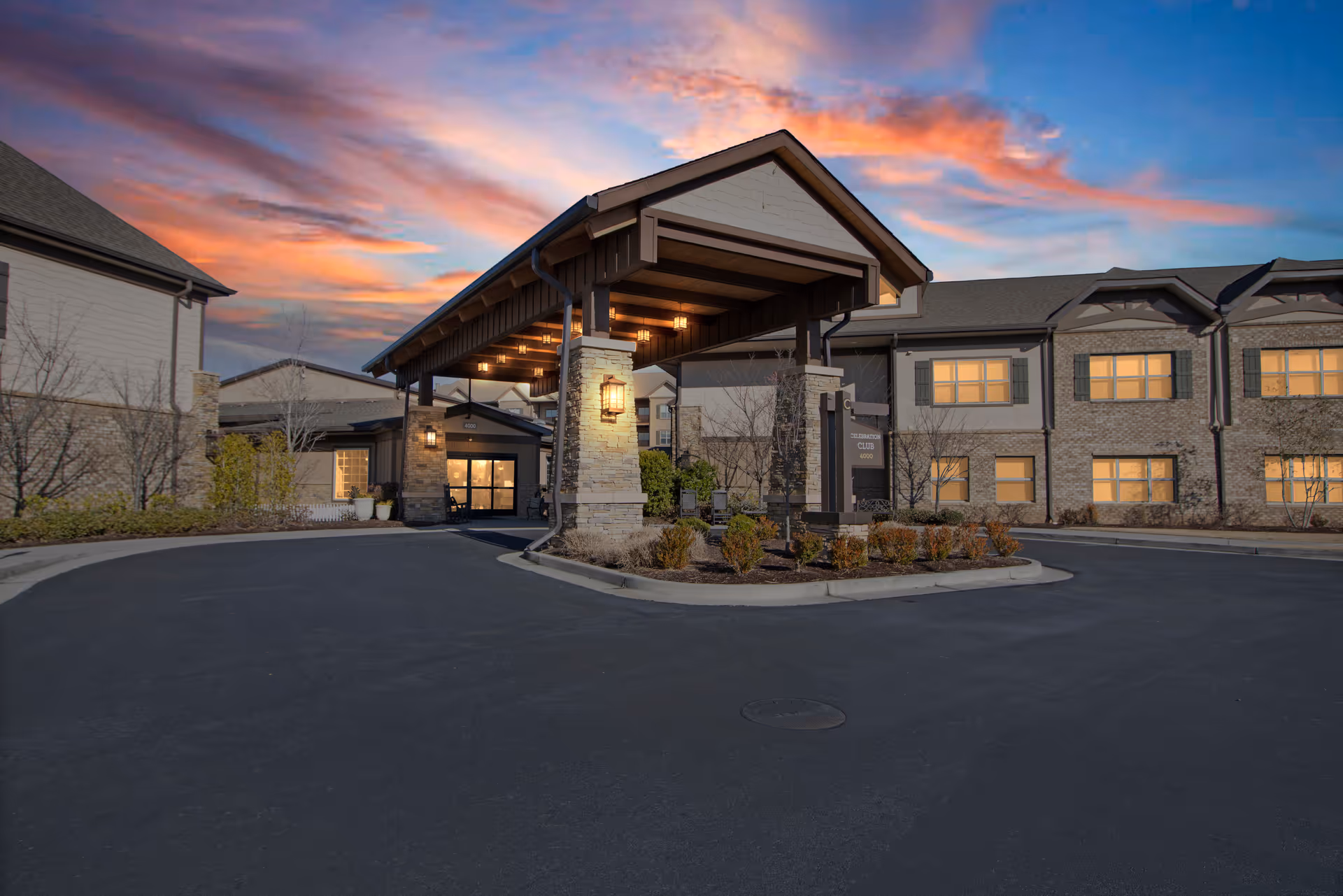 Exterior view of Celebration Village Acworth entrance with circular driveway and stone columns.