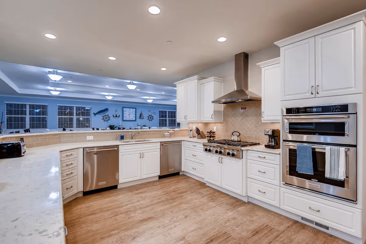 Bright, spacious kitchen with white cabinets, stainless appliances, and a beige tile backsplash.
