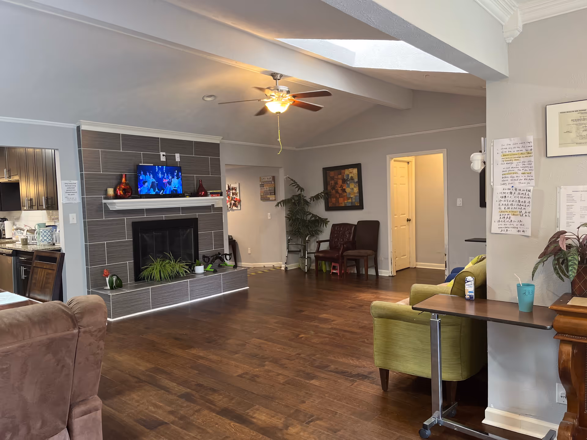 Cozy senior living lounge with fireplace, TV, plants, and seating.