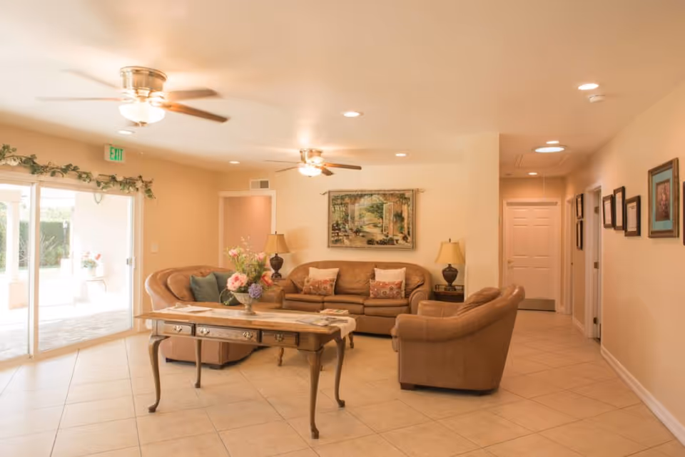 Bright living room with beige seating, wooden coffee table, and sliding glass door.
