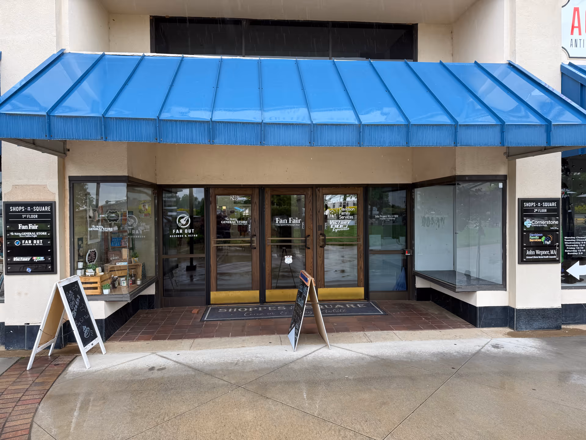 Front entrance of a building with a blue awning and glass doors.
