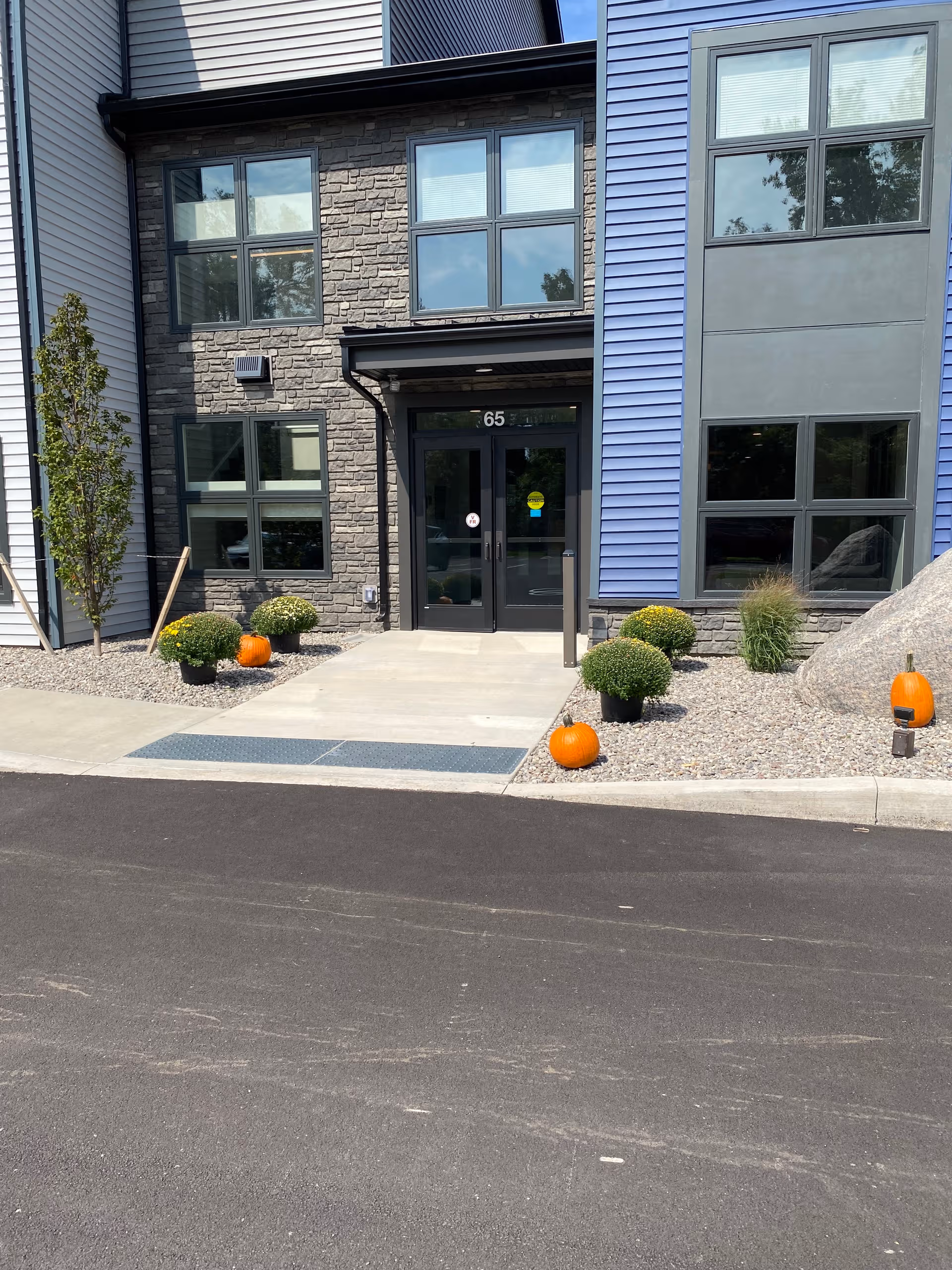 Front entrance of Episcopal SeniorLife Ellen's Place with pumpkins and decorative shrubs.