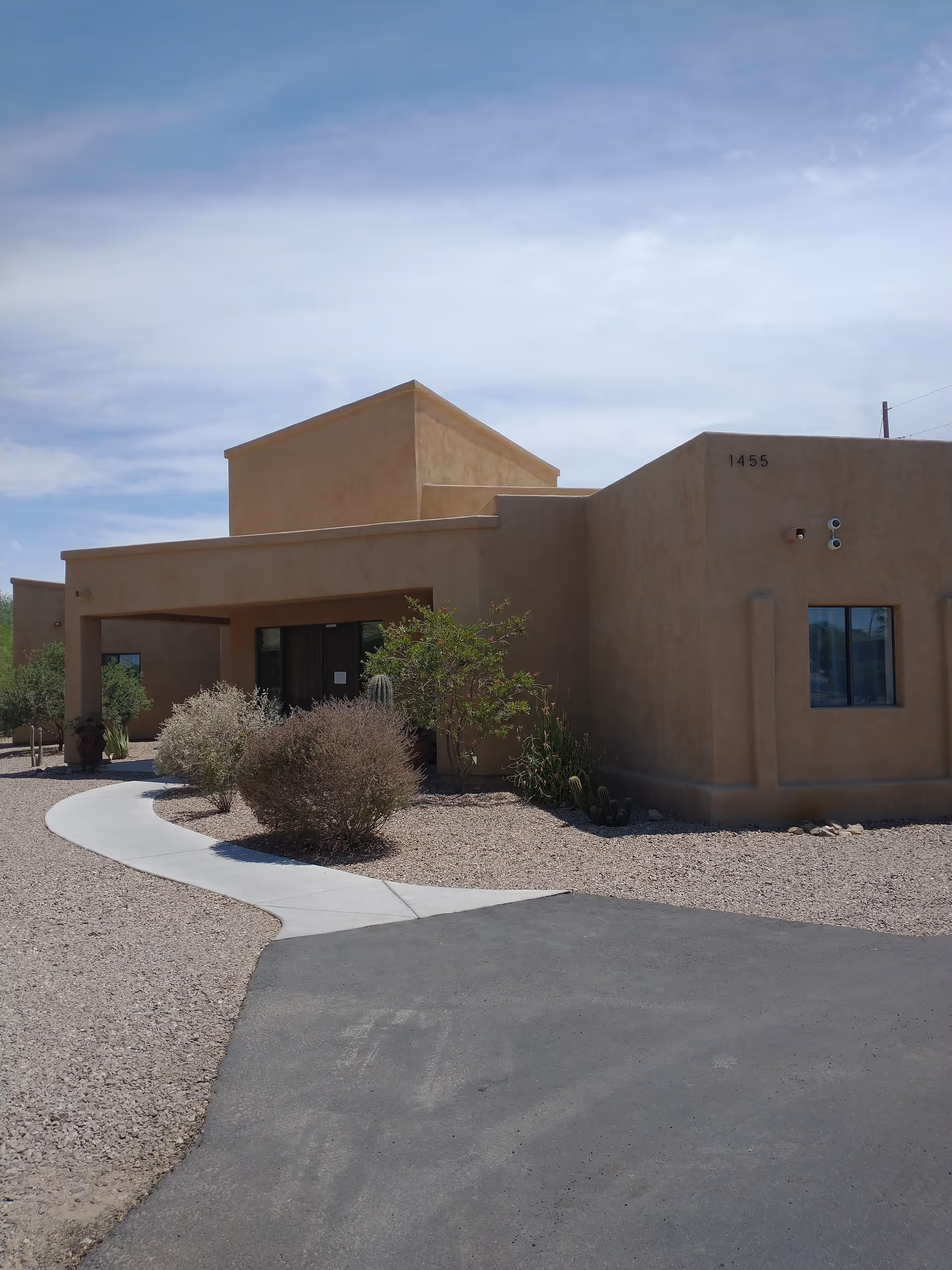 Desert-style assisted living facility exterior with beige stucco walls and a curved walkway.