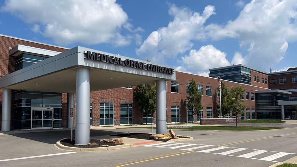 Brick medical building with a covered entrance, tall columns, and a front crosswalk.