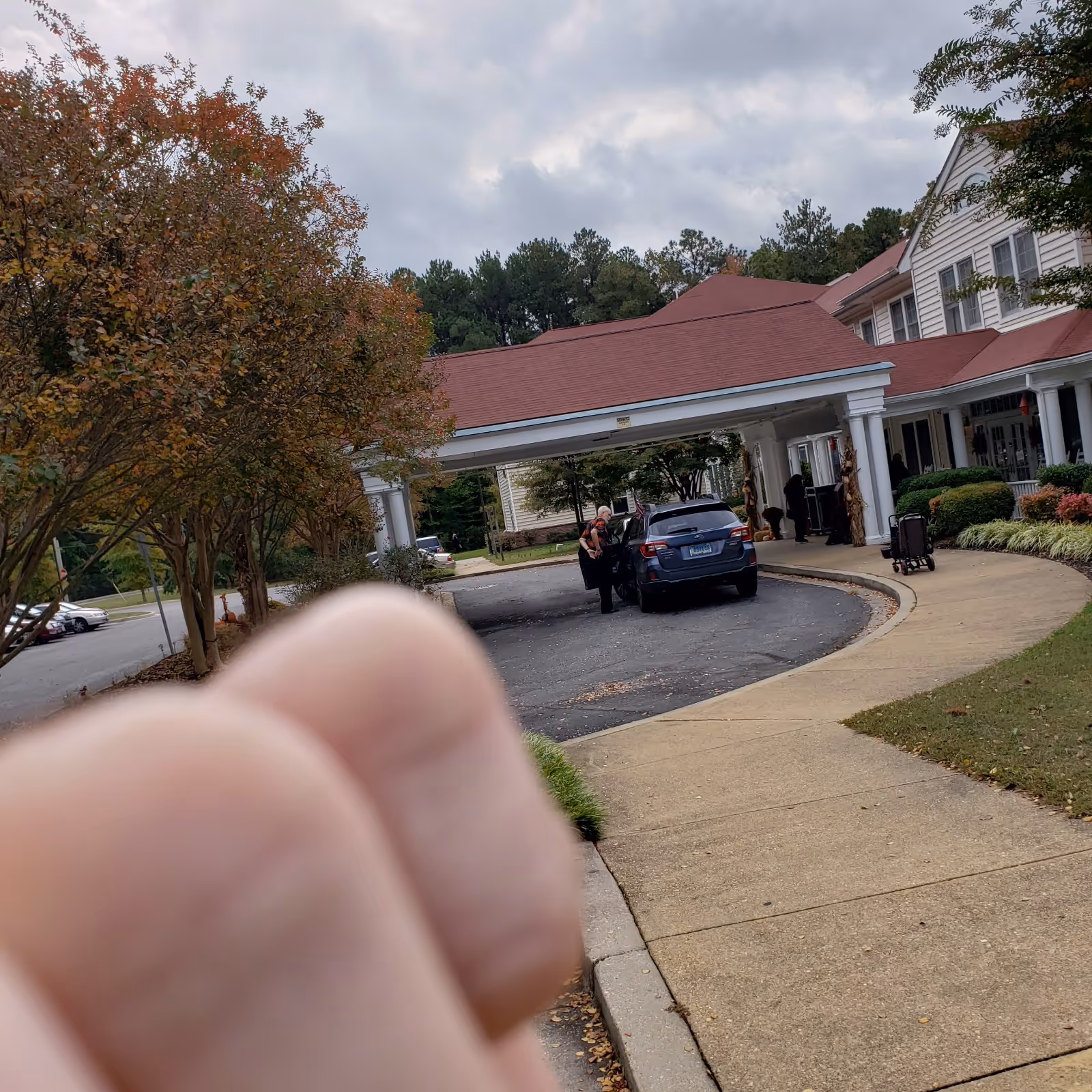 Exterior view of Hermitage at St. John's Creek entrance with car and pedestrians.