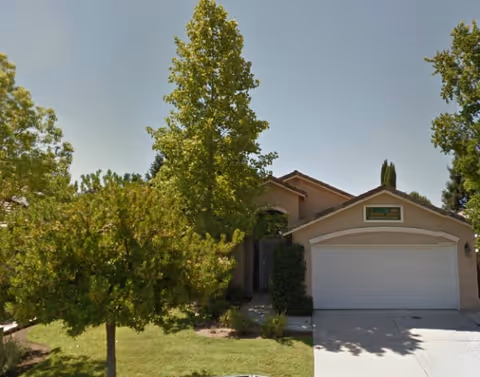 Front view of Garden Terrace Assisted Living facility with a garage, driveway, and trees.