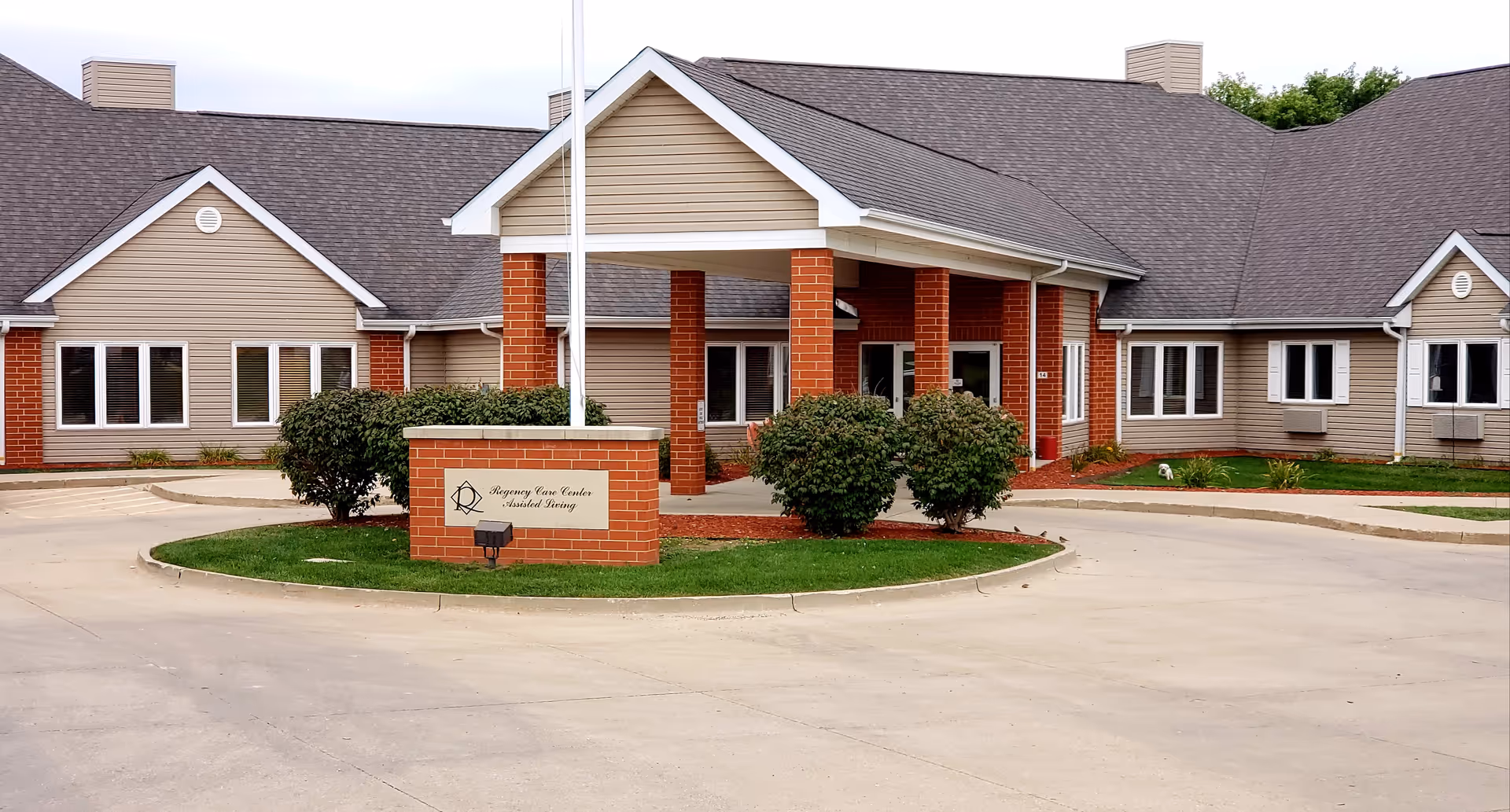 Exterior view of Regency Care Center with circular driveway, entrance, and brick columns.