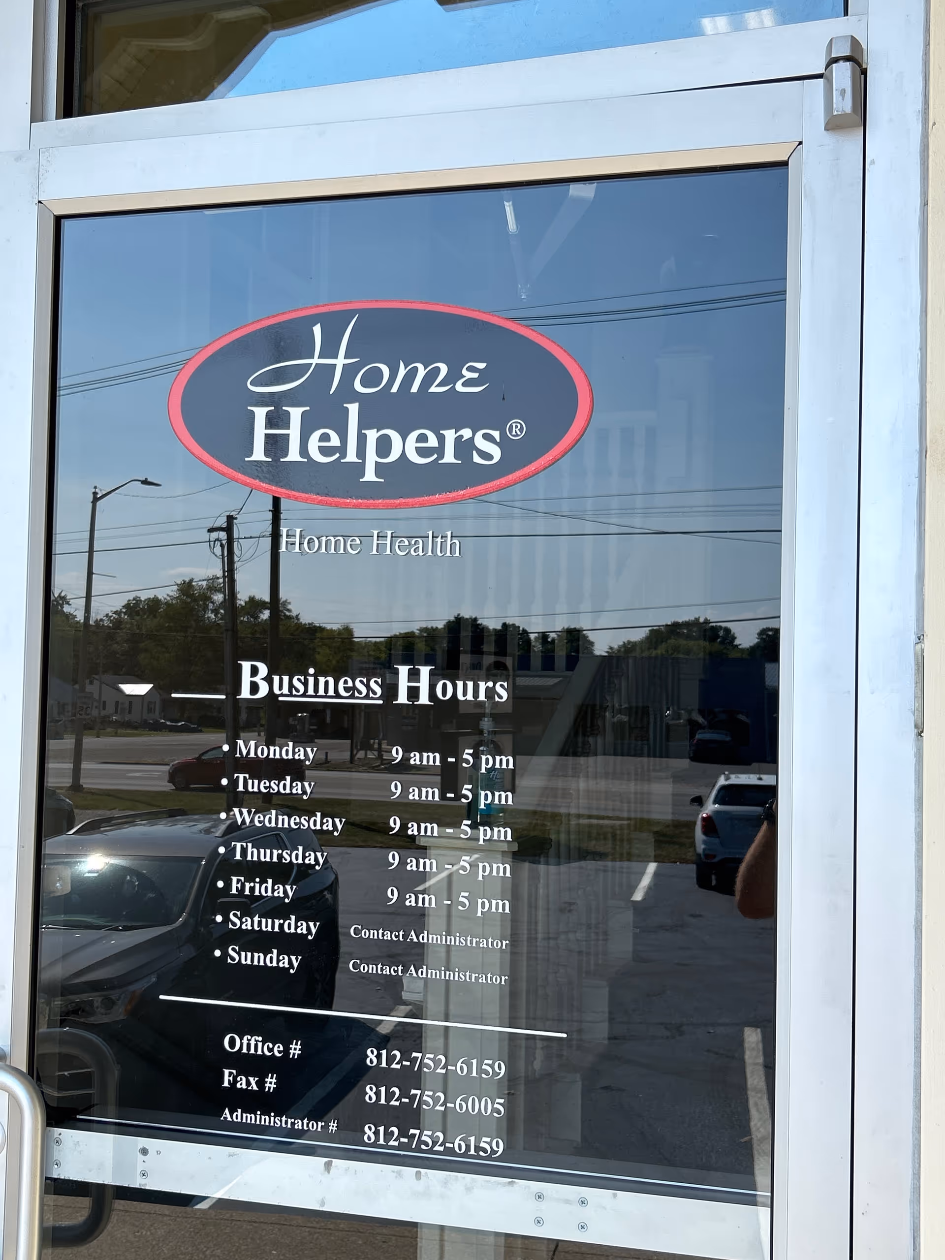 Glass storefront door displays Home Helpers logo and business hours.
