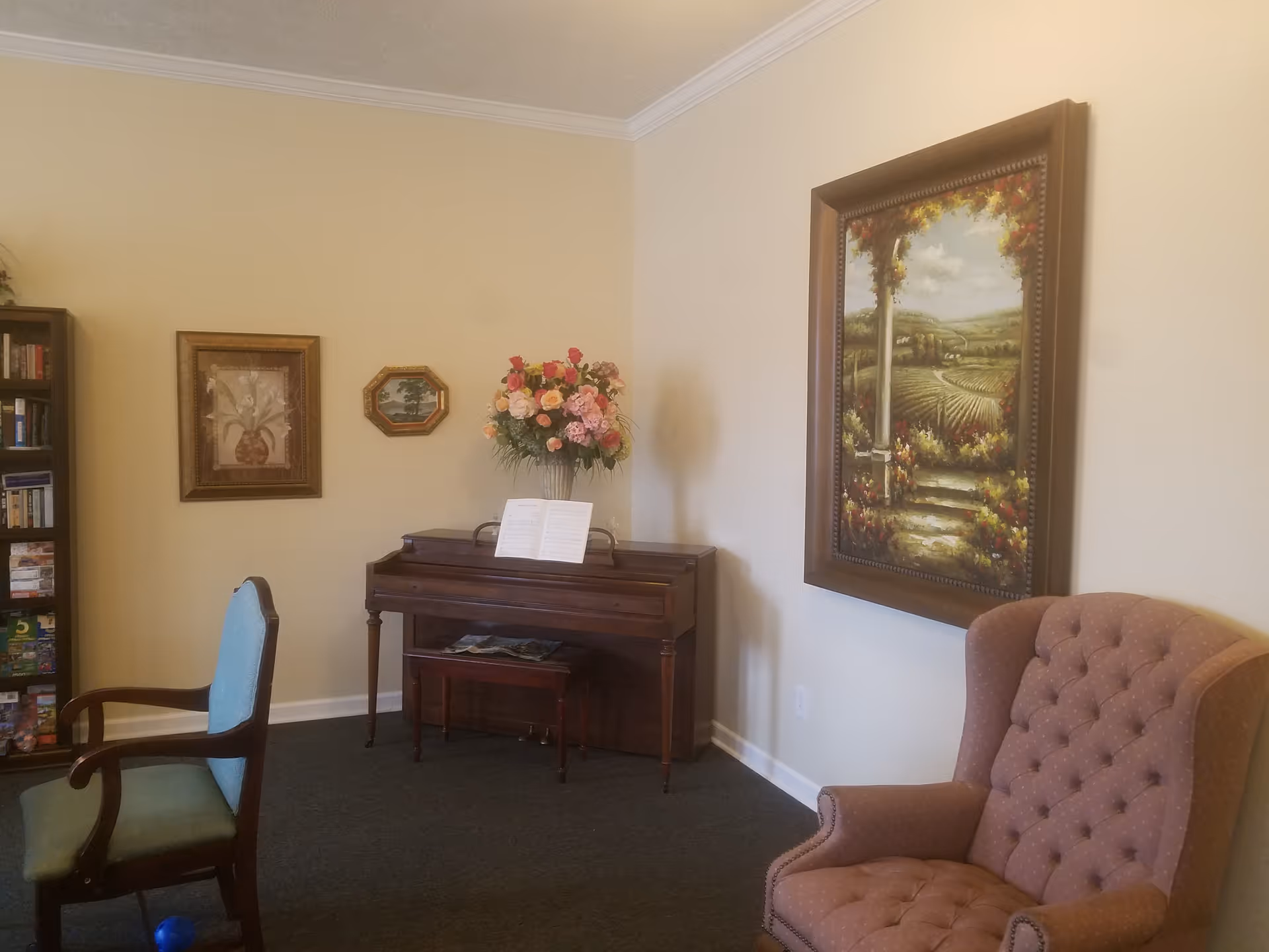 Cozy living room with piano, floral arrangement, wall art, and upholstered seating.