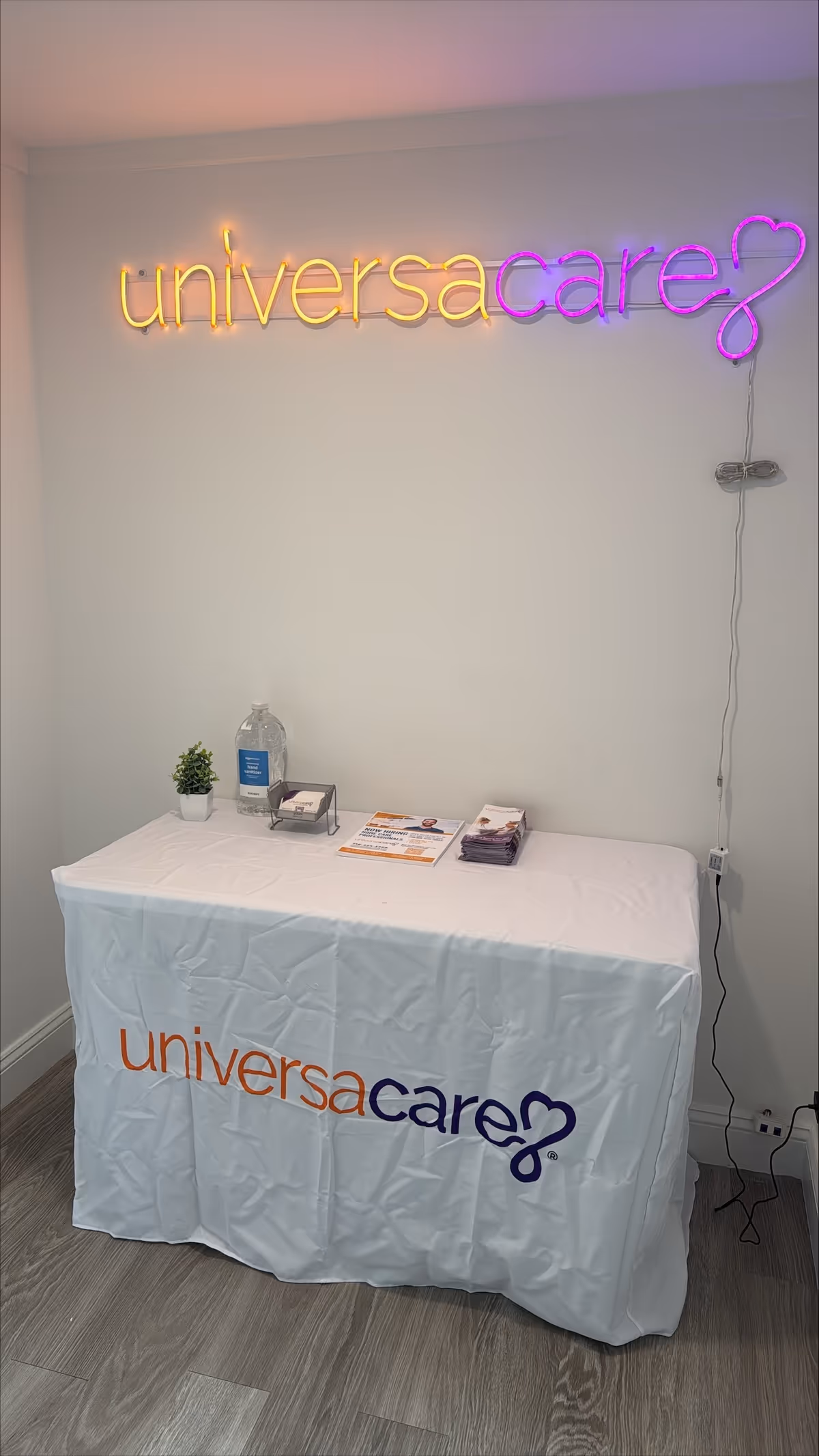 Reception table with UniversaCare banner and neon sign in a bright lobby