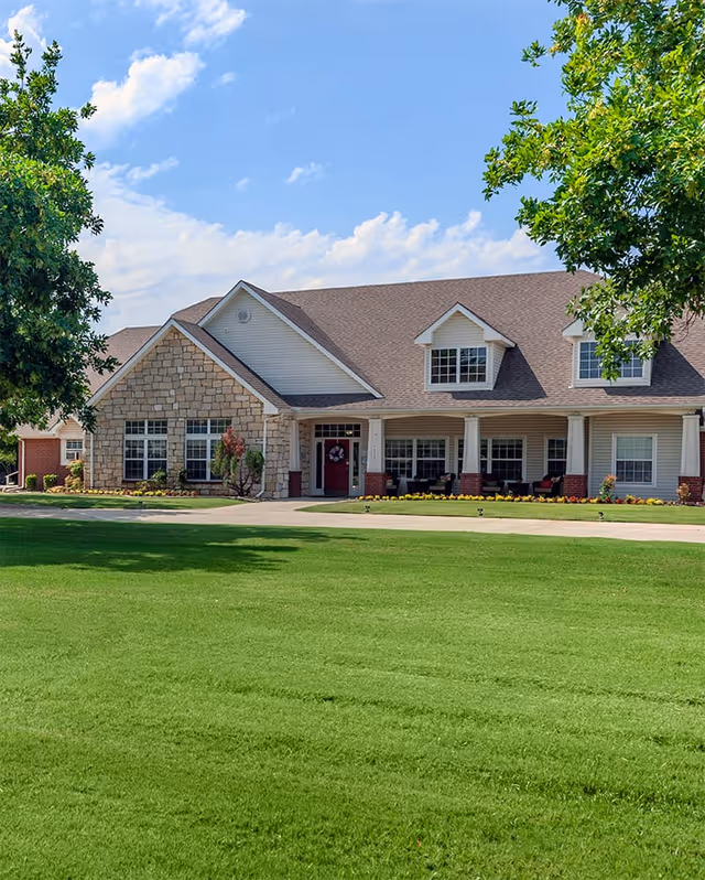 A single-story senior living facility with stone accents, front entrance, and green lawn