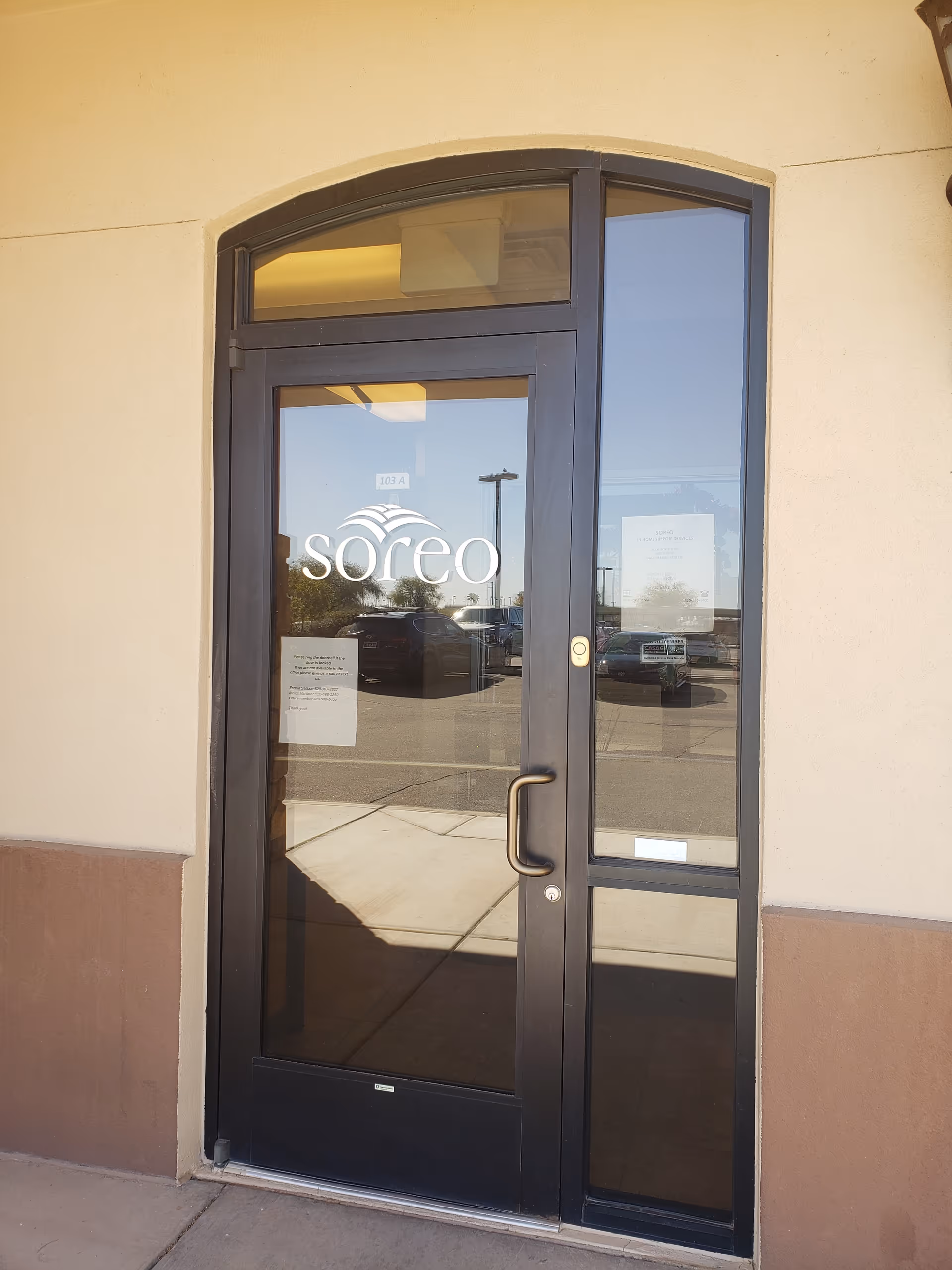 Glass door entrance with Soreo logo on a beige exterior wall of a senior facility.