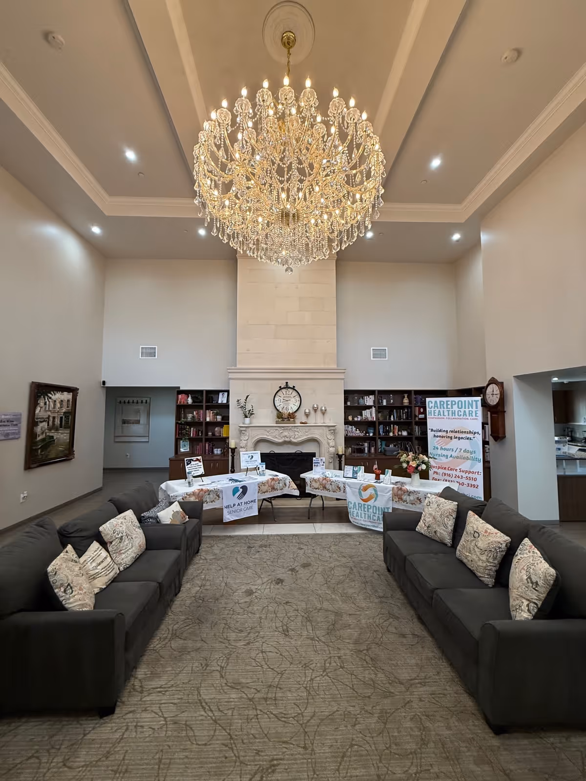 Elegant lobby lounge with chandelier, two sofas, and a central fireplace.