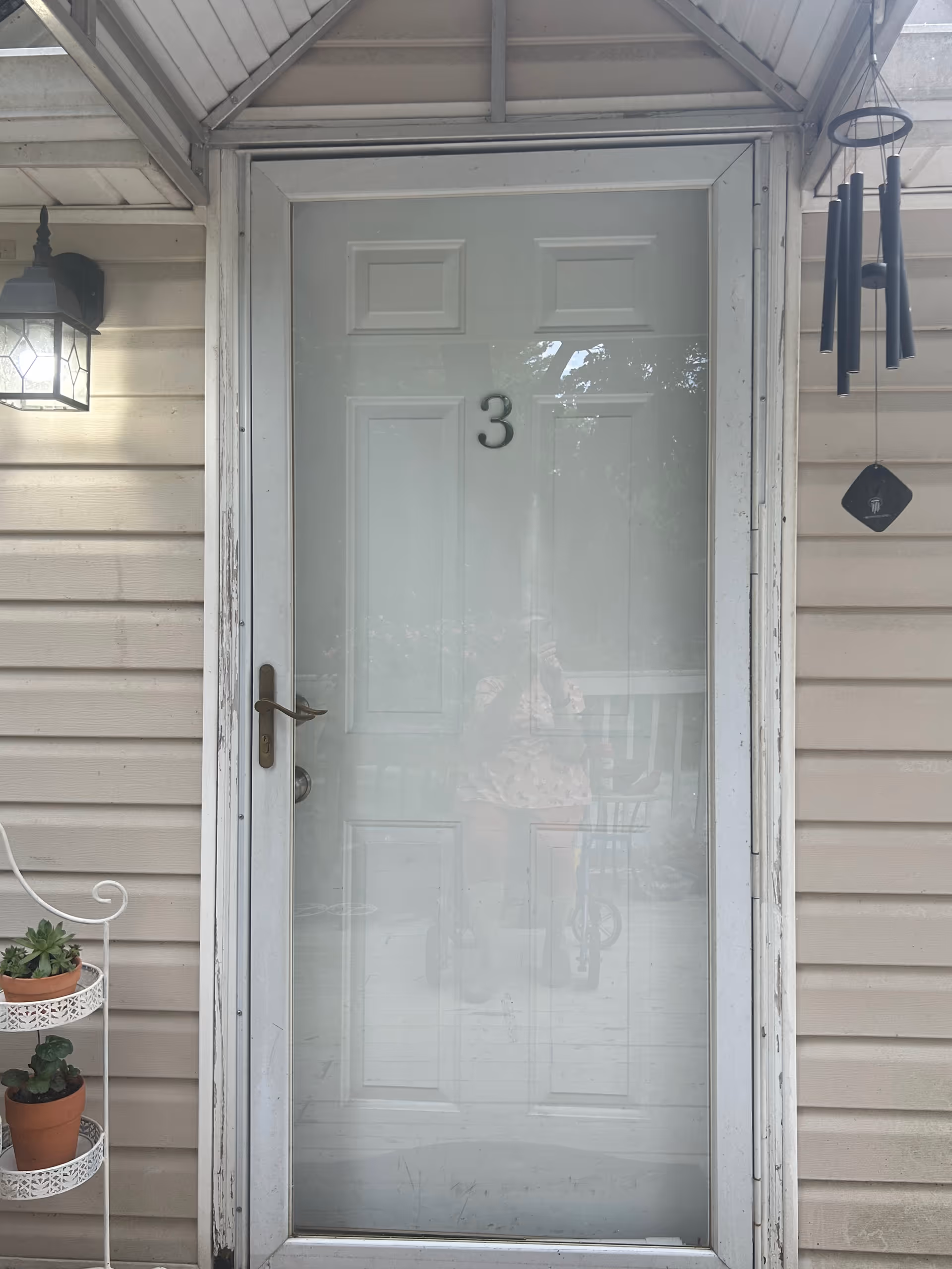 Front door with frosted glass and house number 3, framed by beige siding.