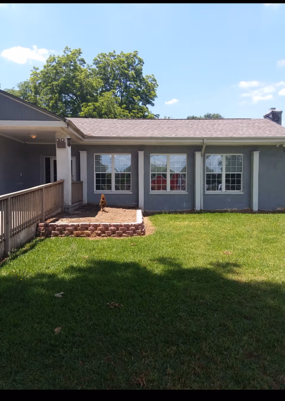 Single-story gray facility exterior with large windows, brick steps, and a grassy yard.