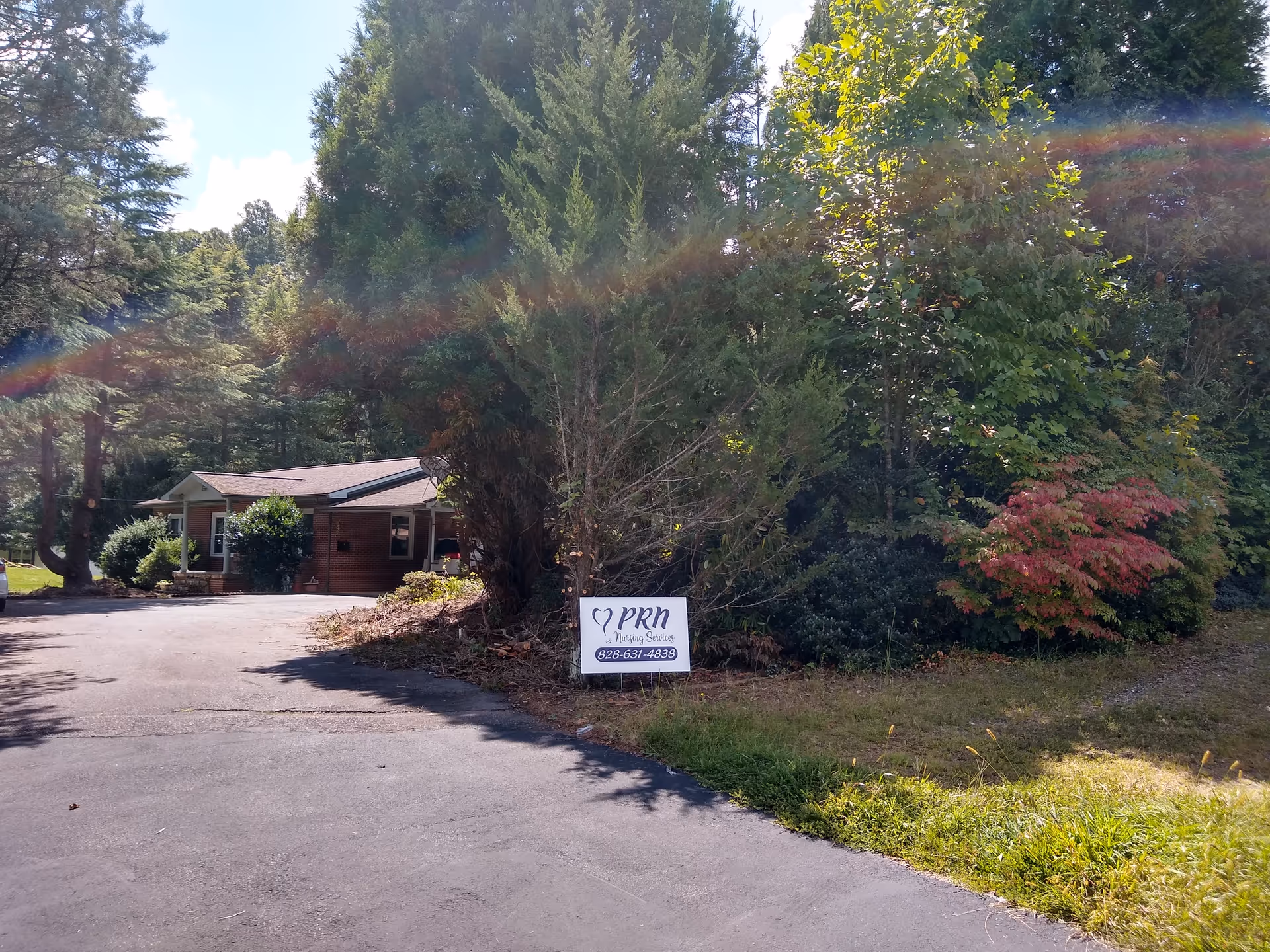 Single-story facility entrance with a sign reading PRN Nursing Services amid trees.