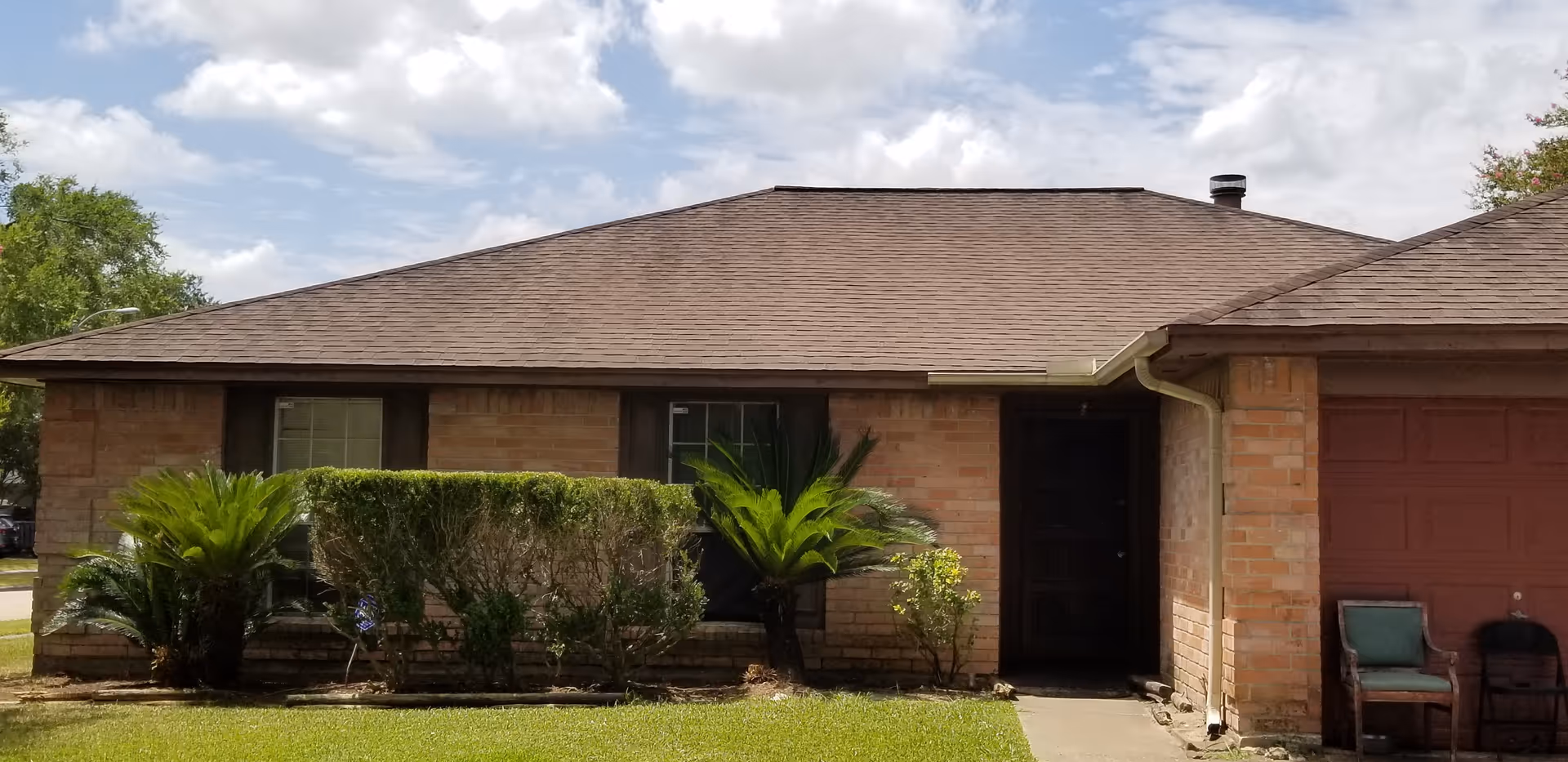 Single-story brick senior care facility exterior with shrubs, palm plants, and a driveway.