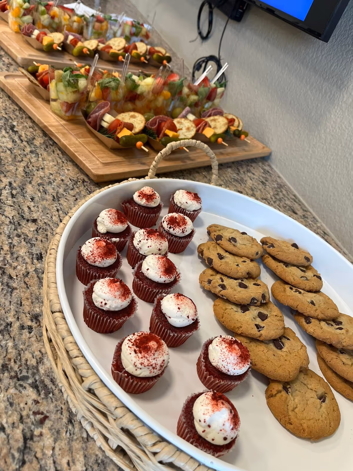 Assorted cupcakes, cookies, and fruit skewers displayed on a granite counter.