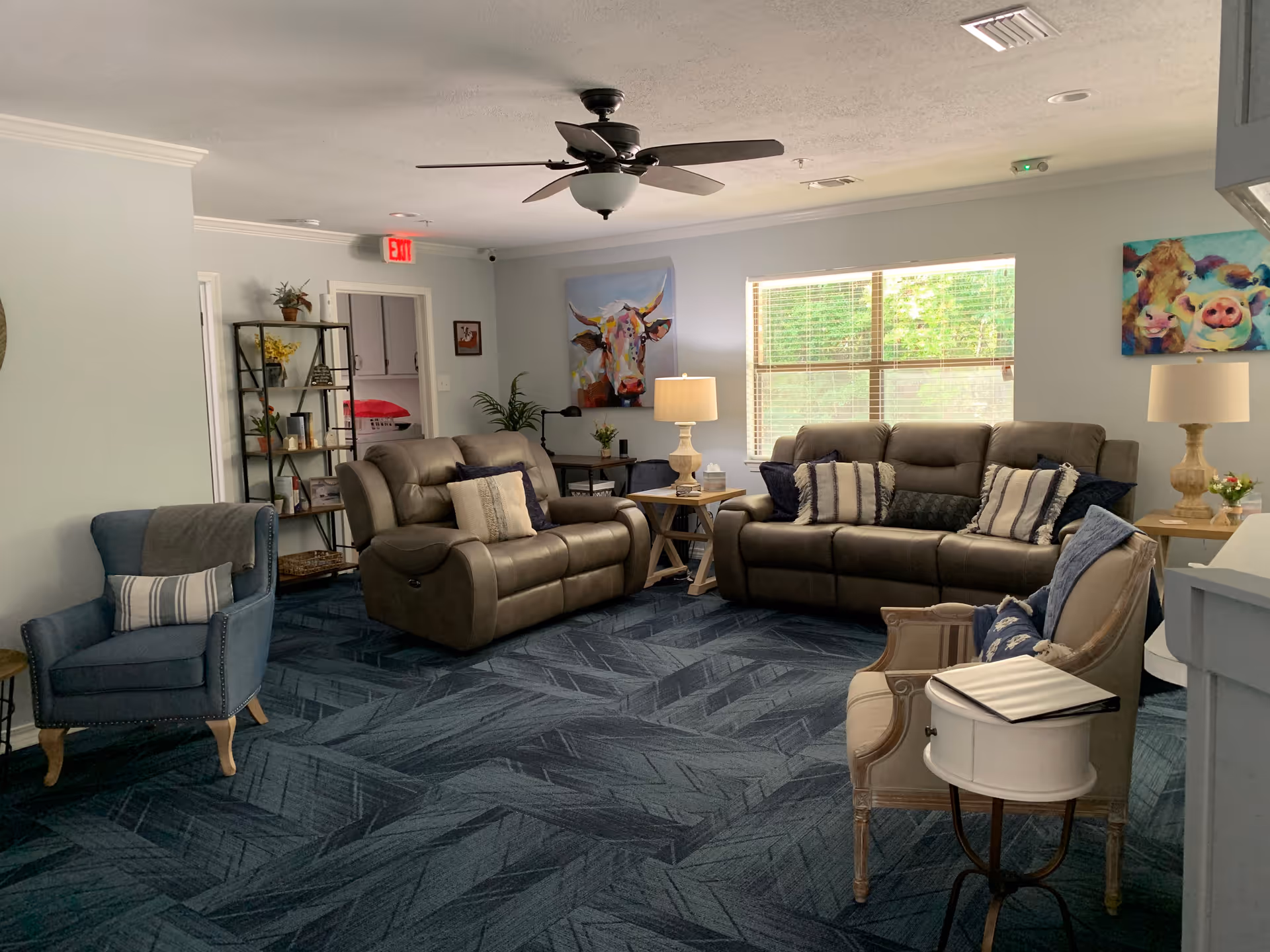 Cozy living room lounge with leather sofas, chairs, and artwork in a bright common area.