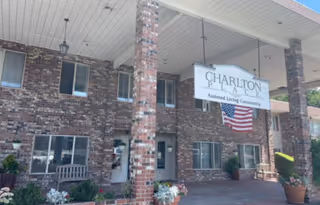 Brick building entrance with a Charlton Place sign and an American flag on the porch