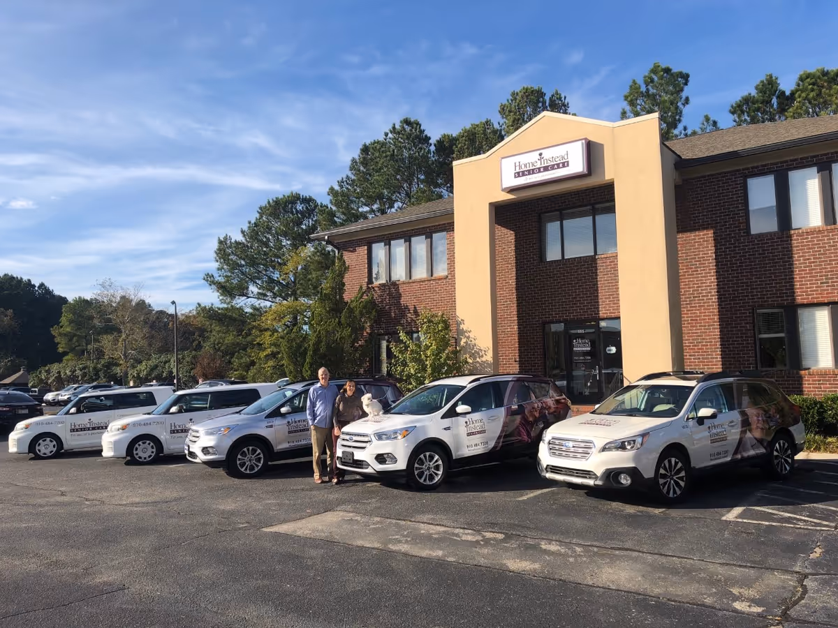 Exterior view of Home Instead Senior Care building with parked company vehicles.