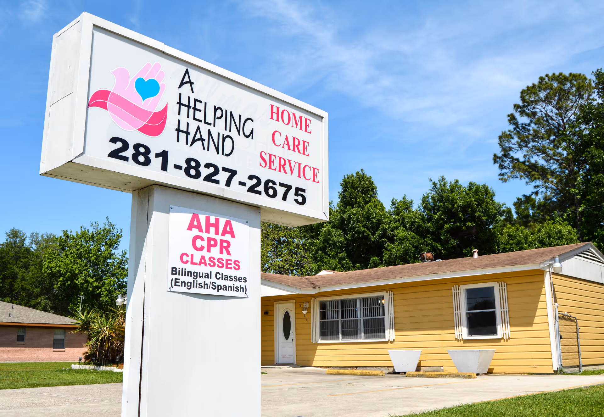 Large sign for A Helping Hand Home Care Service beside a yellow, single-story building.