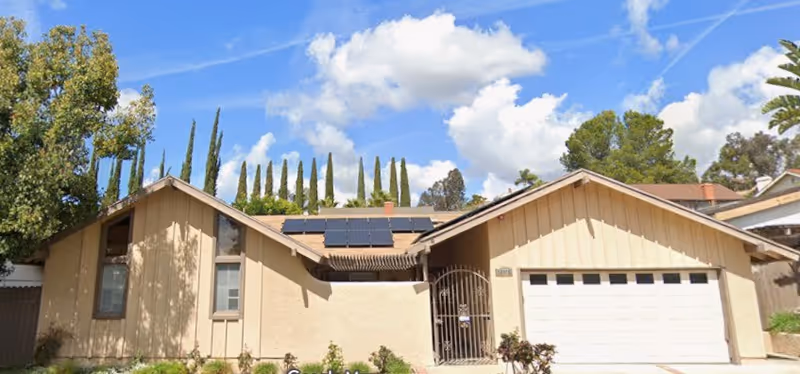 Single-story beige senior living facility with a gated entrance and attached garage.