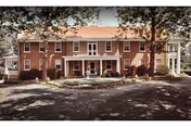Two-story brick Fremont Home senior living facility exterior with a centered entrance and trees.