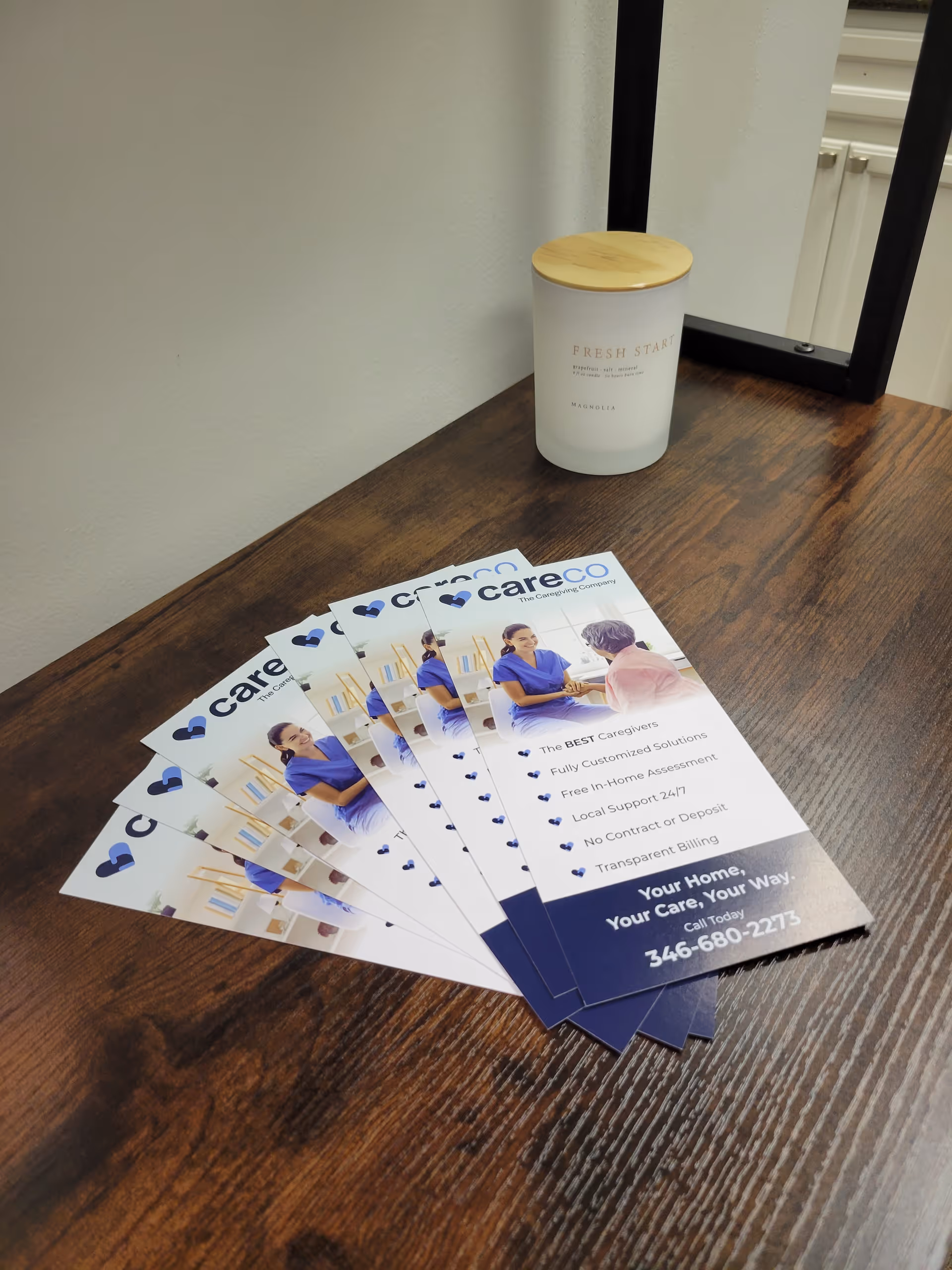 Wooden table with CareCo brochures and a white container on a dark surface.