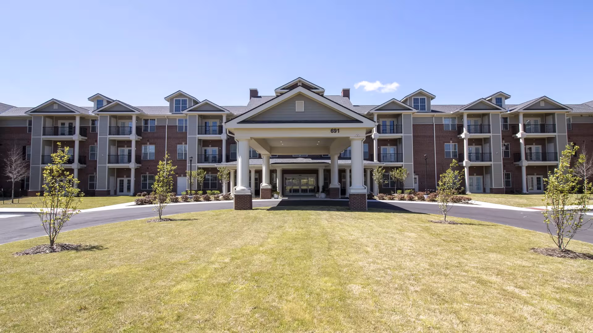 Exterior view of StoryPoint Collierville's brick senior living building with a central covered entrance.