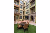 Outdoor courtyard with a round table and chairs amid a multi-story building.