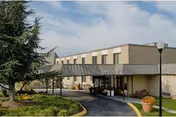 Exterior view of a senior living facility with a covered entrance and landscaped surroundings.